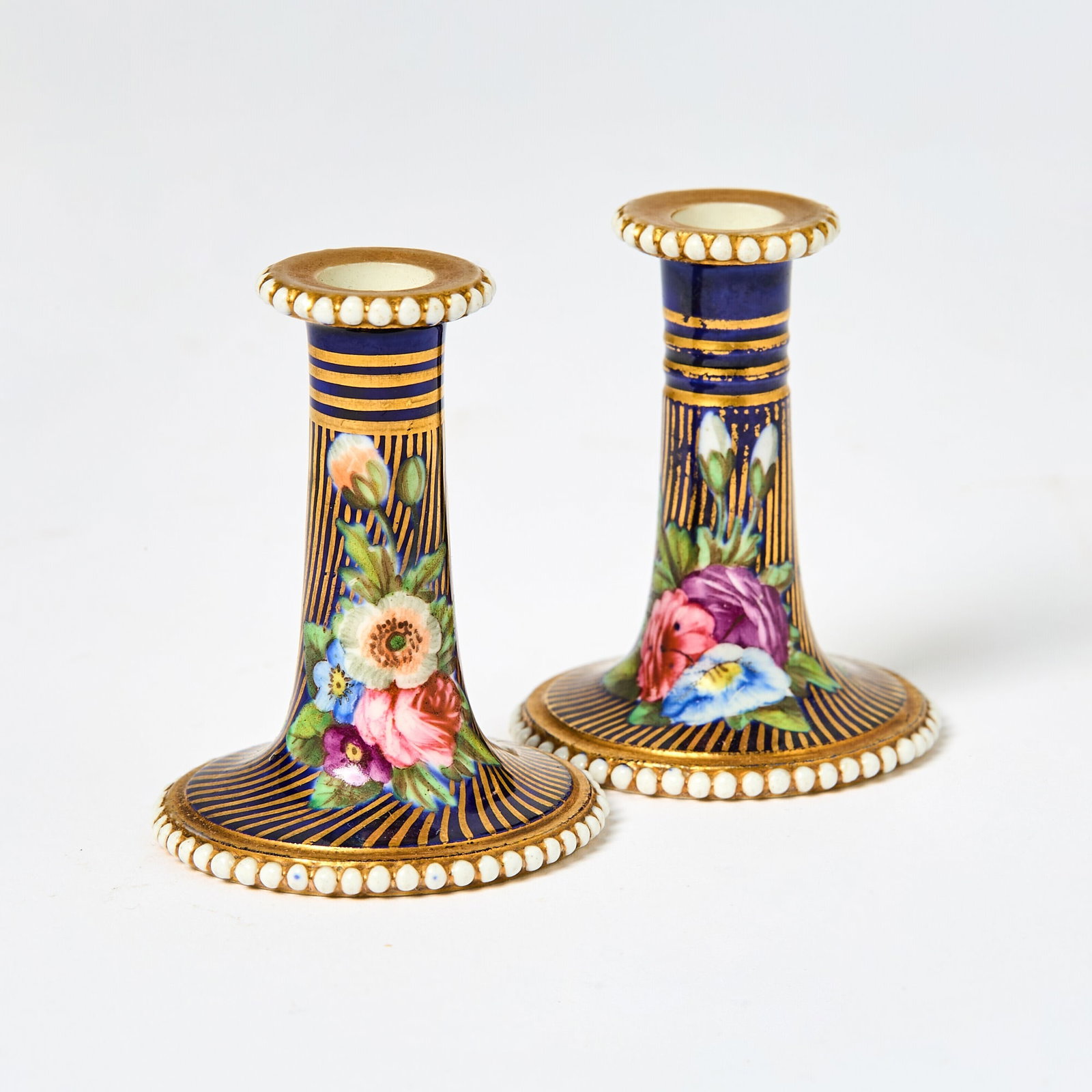 Pair of Spode Gilt and Polychrome Blue Ground Miniature Candlesticks: Early 19th Century Each with cylindrical stem, beaded borders and round base, painted in coloured enamels with flowers and leaves, on a blue and gilt spirally striped ground, painted marks in red and