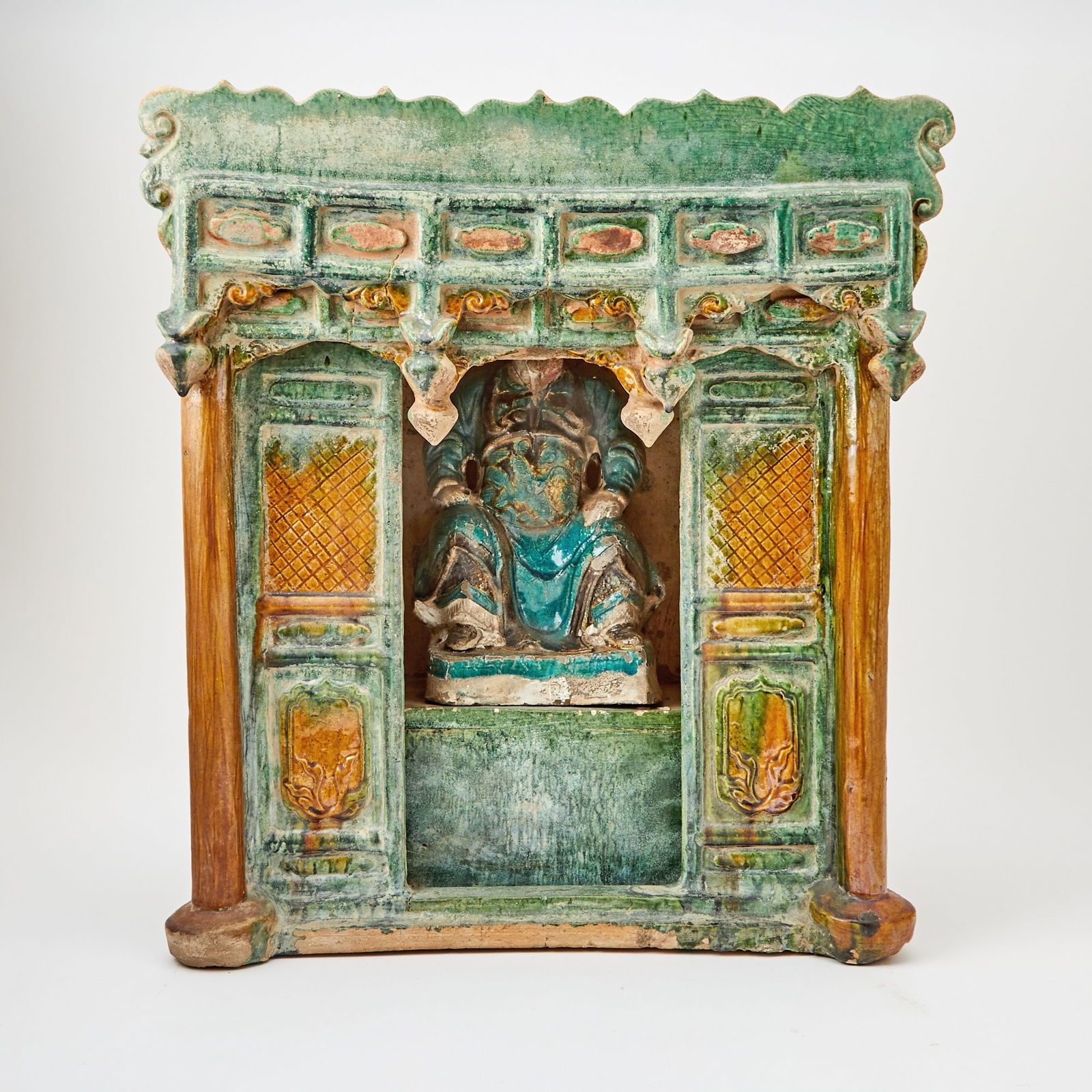 Chinese Glazed Pottery Figure of Guandi and Shrine Ming Dynasty: The seated god of prosperity paired with the model of a shrine wall with a niche. (Height 18 1/2 inches)