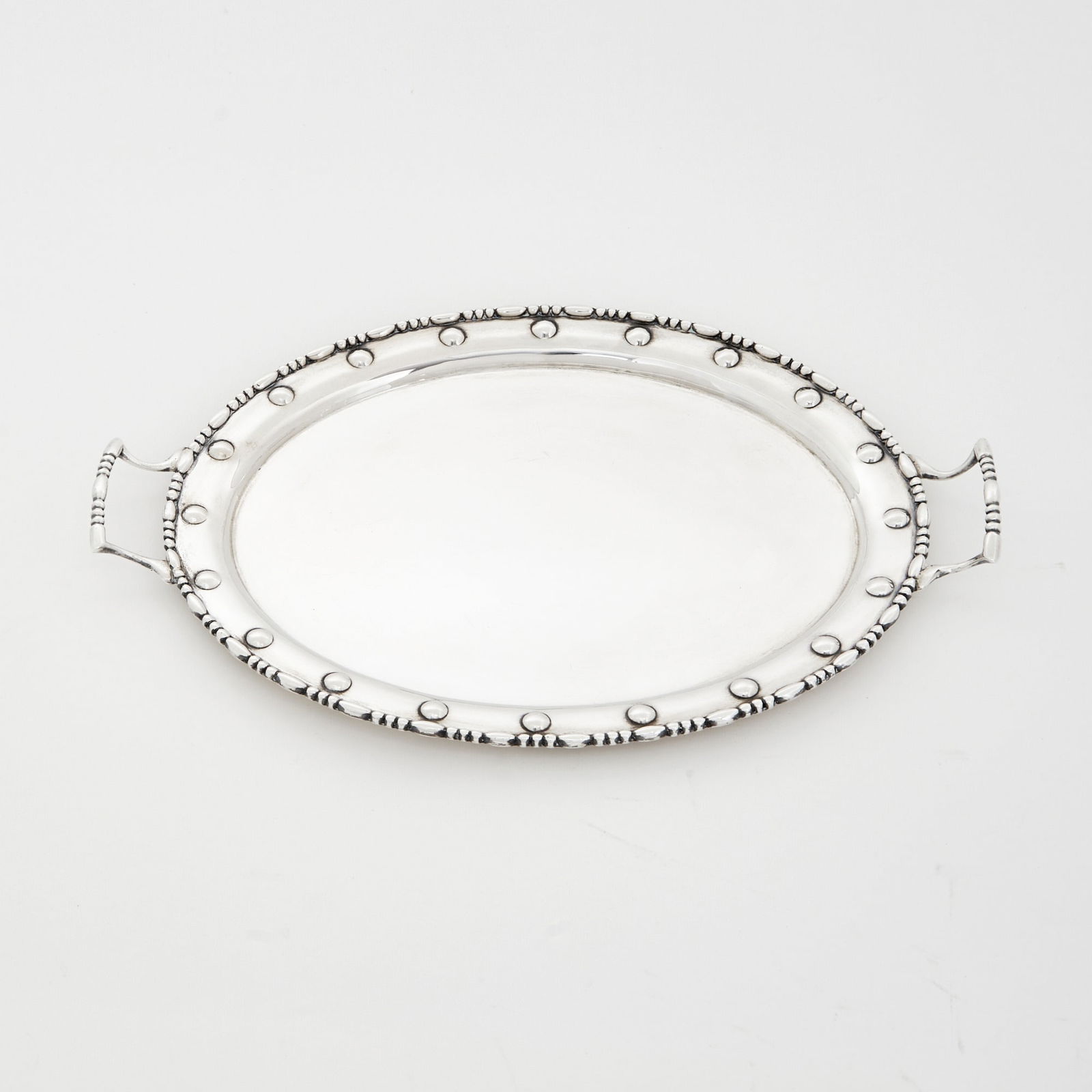 Edward VII Sterling Silver Two Handled Tray: Elkington & Co., London, 1906Oval with wide riveted border, with loop handles. Length over handles 14 1/2 inches, approximately 21 ounces. Generally good condition overall; light surface