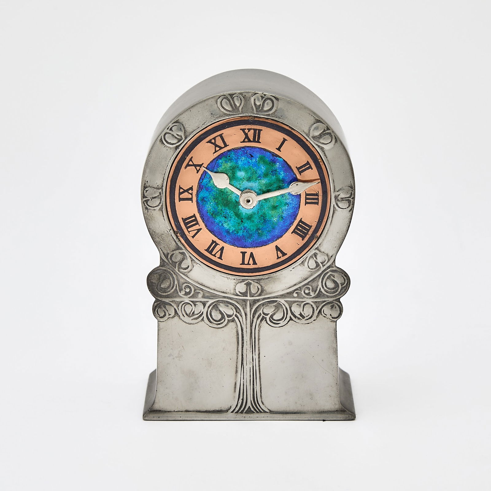 Liberty & Co. Art Nouveau Tudric Pewter, Copper and Enamel Desk Clock: Model no. 0636, early 20th century The front of the flattened case cast as a stylized tree with a circular crown, the conforming dial with a mottled cobalt blue and deep emerald green center, impresse