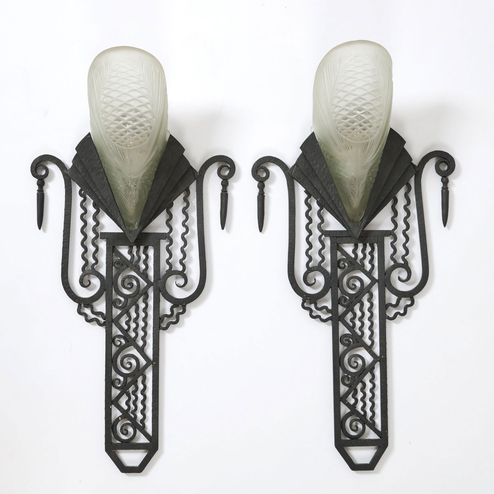Pair of Sabino Art Deco Molded Glass and Wrought Iron "Pine Cone" Two-Light Wall Sconces: Circa 1930 Each with a geometricized foliate openwork backplate, unmarked, with a central shade molded with stylized pine cones and pine needles, in colorless glass, satin finish, signed SABINO. Heigh