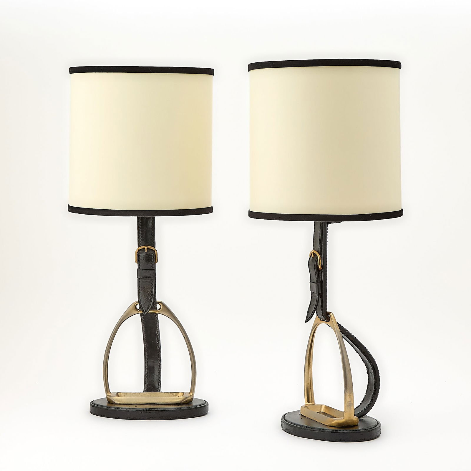 Pair of Longchamp Paris Gilt-Metal and Leather Equestrian Themed Table Lamps: Mid-20th centuryIn the style of Hermès, each unmarked.Height overall 20 inches; height of body 11 3/4 inches. Black overpaint on black leather; each electric wire has been cut; each will need