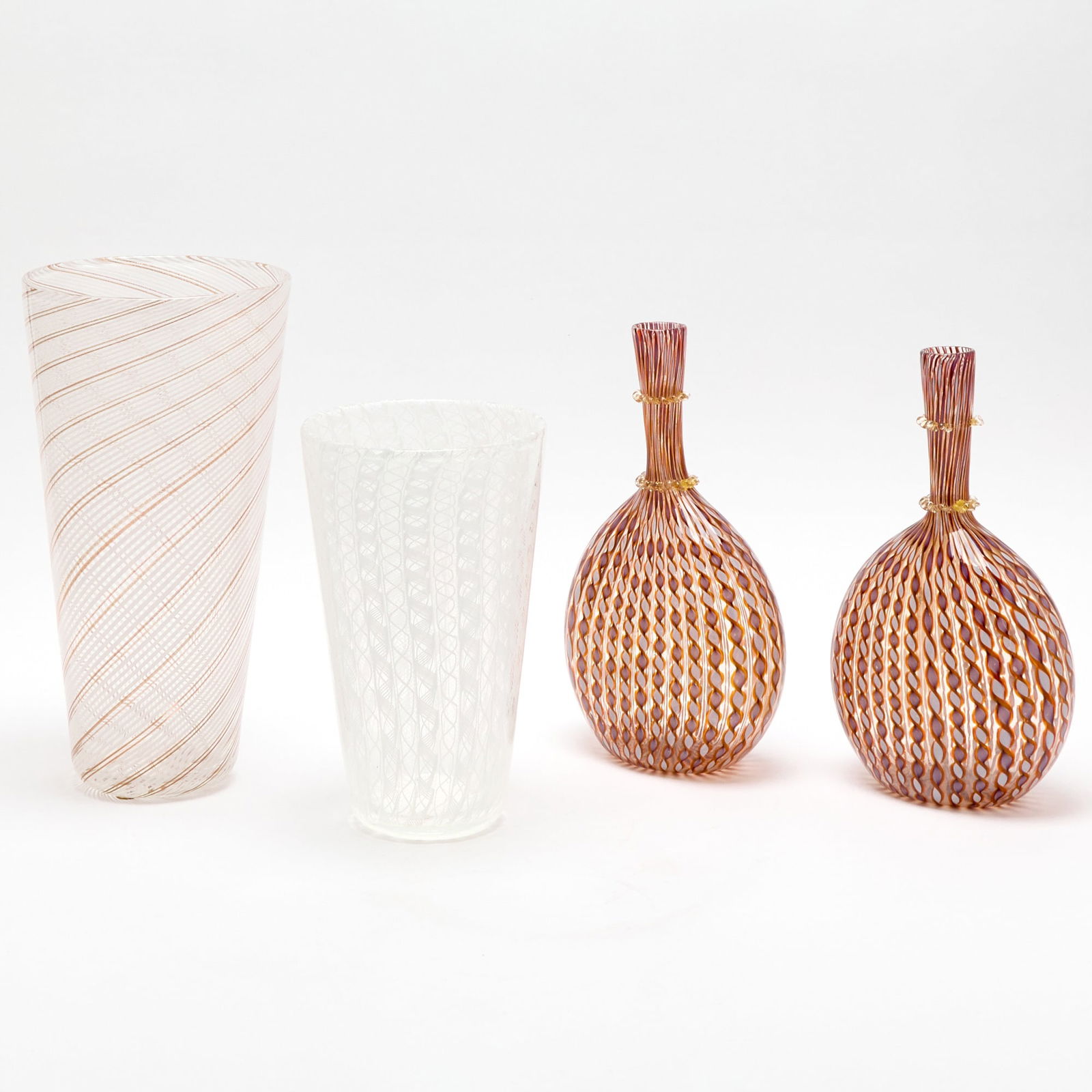 Group of Murano Blown Glass Vases: Comprising a tapering cylindrial example, in lattimo, aventurine and colorless glass, with diagonal stripe decoration, unmarked, height 12 1/4 inches; another tapering cylindrical example, with lattic