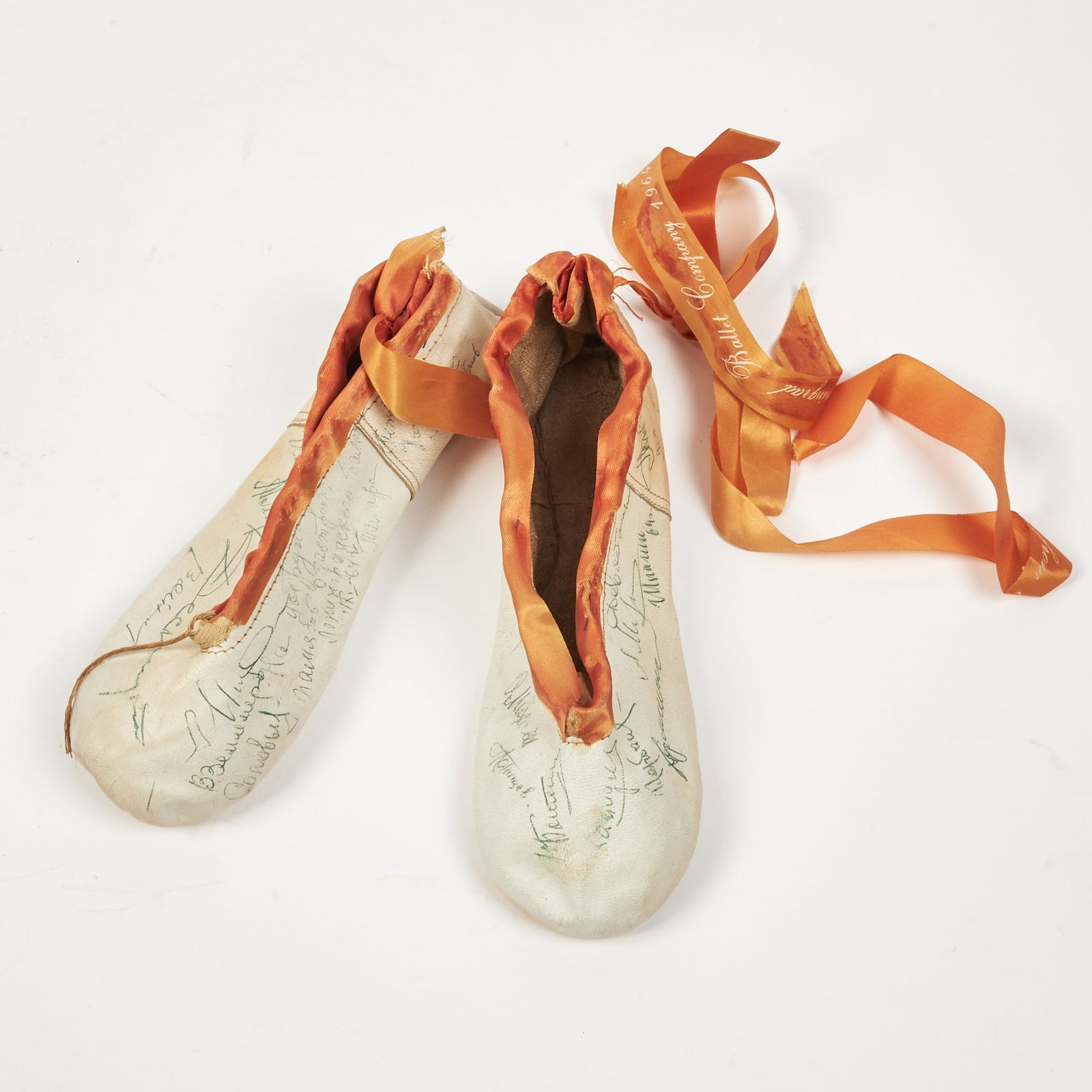 Leningrad Ballet signed slippers from their 1964 U.S. tour: LENINGRAD BALLETA pair of ballet slippers with various signatures of members of the Leningrad Ballet. A pair of white ballet slippers with silk accenting, a matching ribbon is tied-in and is insribed