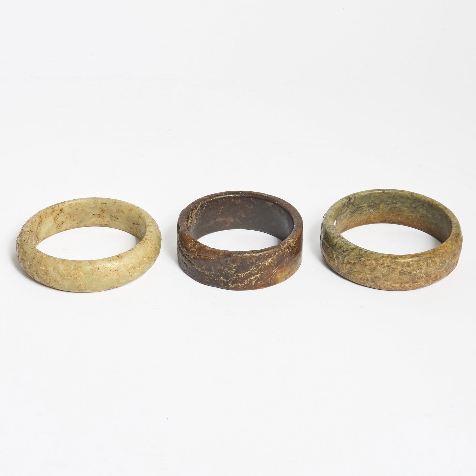 Three Chinese Archaic Jade Bangles: Each carved from mottled nephrite. (Diameter of largest 3 1/2 inches)