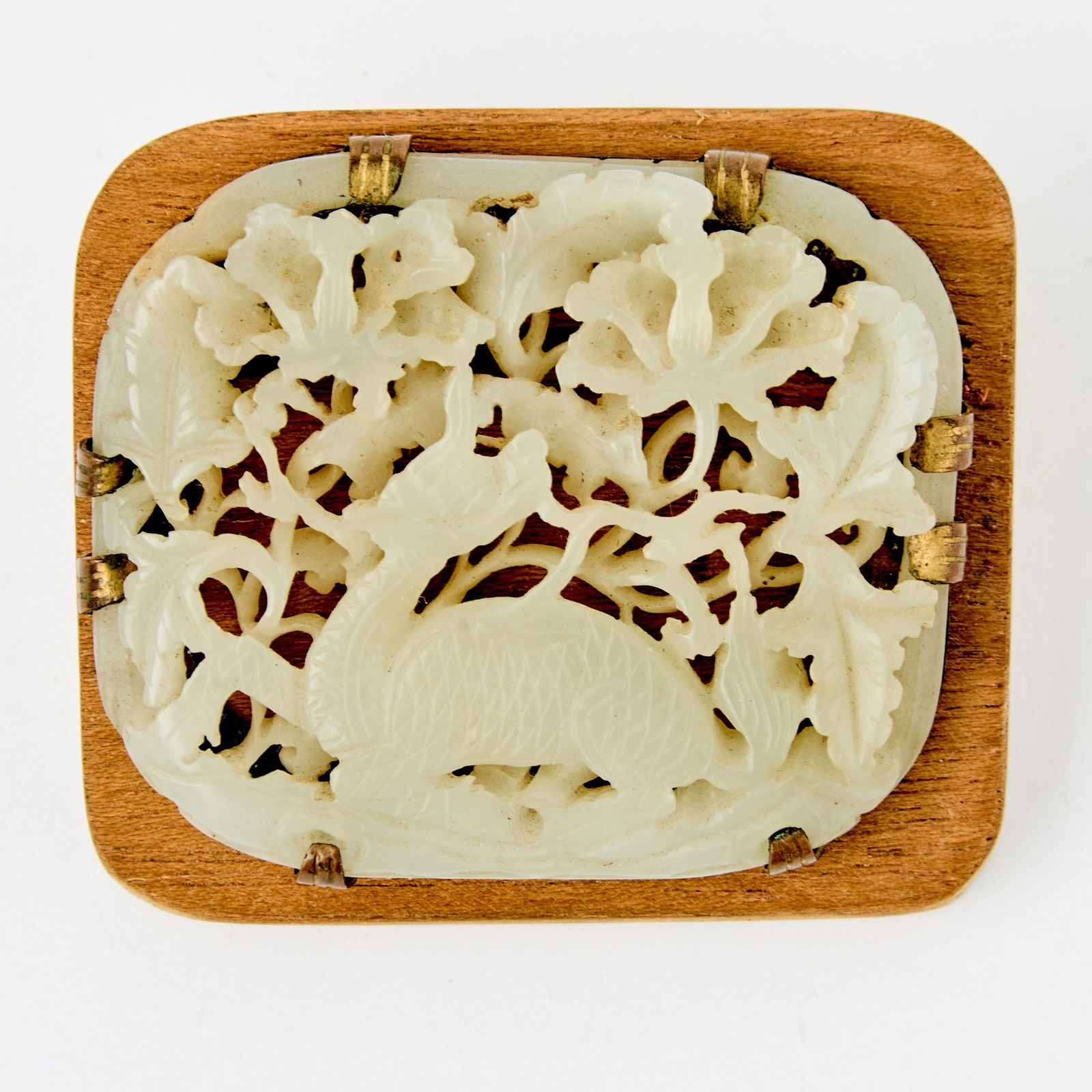 A Chinese Reticulated Jade Plaque Yuan-Ming Dynasty: Carved in openwork with a recumbent qilin turning its head back, amidst scrolling leafy vines bearing blossoms. (Length 2 1/4 inches)