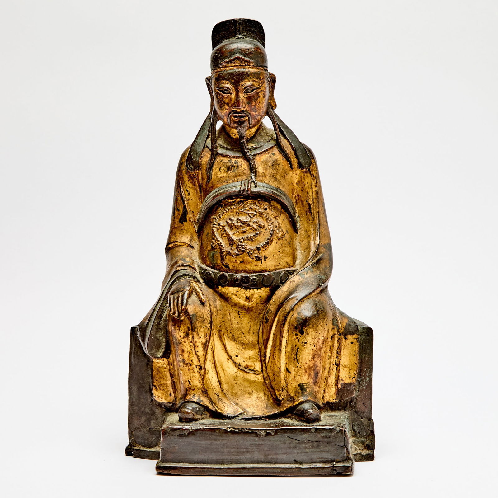 A Chinese Gilt Lacquered Bronze Figure of Wenchang Ming Dynasty: The seated, bearded figure depicted in typical offical's garb of a dragon robe and court hat and cast atop a vented platform base. (Height 13 inches)