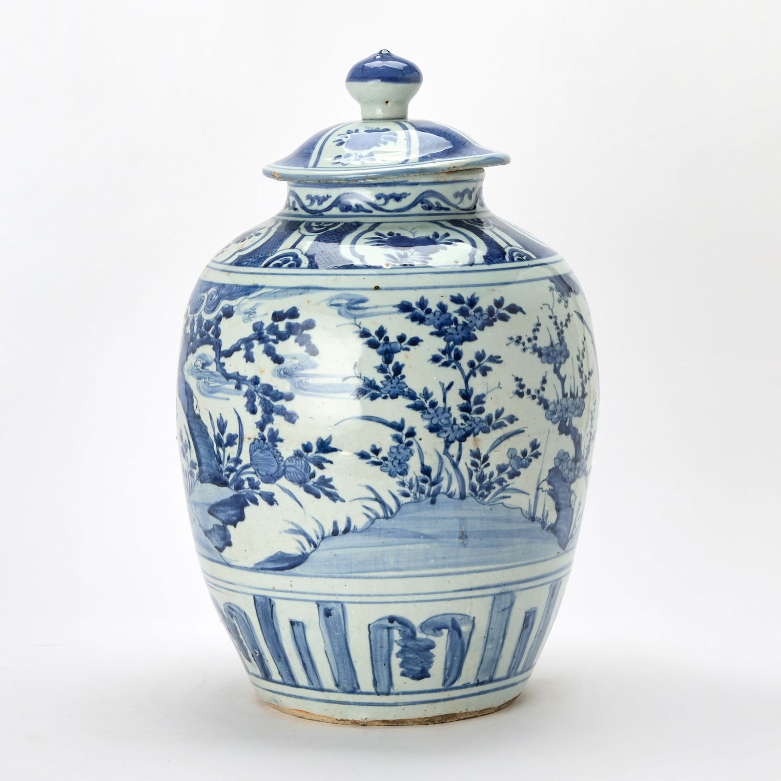 A Chinese Blue and White Porcelain Covered Jar Wanli Period: The ovoid body surmounted by a domed cover with a bud-form finial; decorated with a pair of phoenix, one perched on rockwork and the other in flight amid blossoming trees. (Height 20 1/2 inches) March