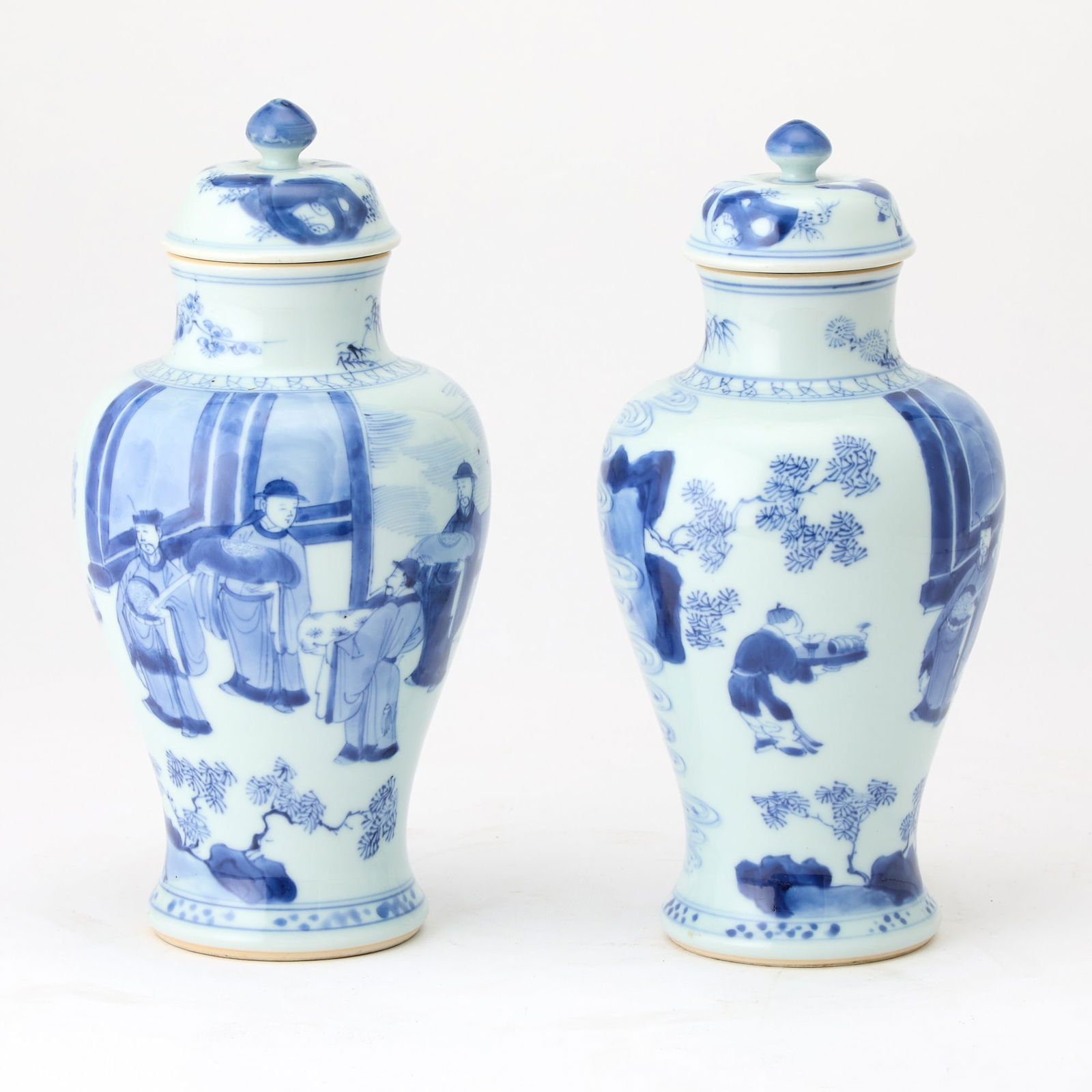 A Pair of Chinese Blue and White Porcelain Vases and Covers Kangxi Period: Each of baluster form, the body surmounted by a domed cover with a pointed knop, and decorated with a court official attended by attendants and noblemen at a pavilion entrance. (Height 9 inches) Chait
