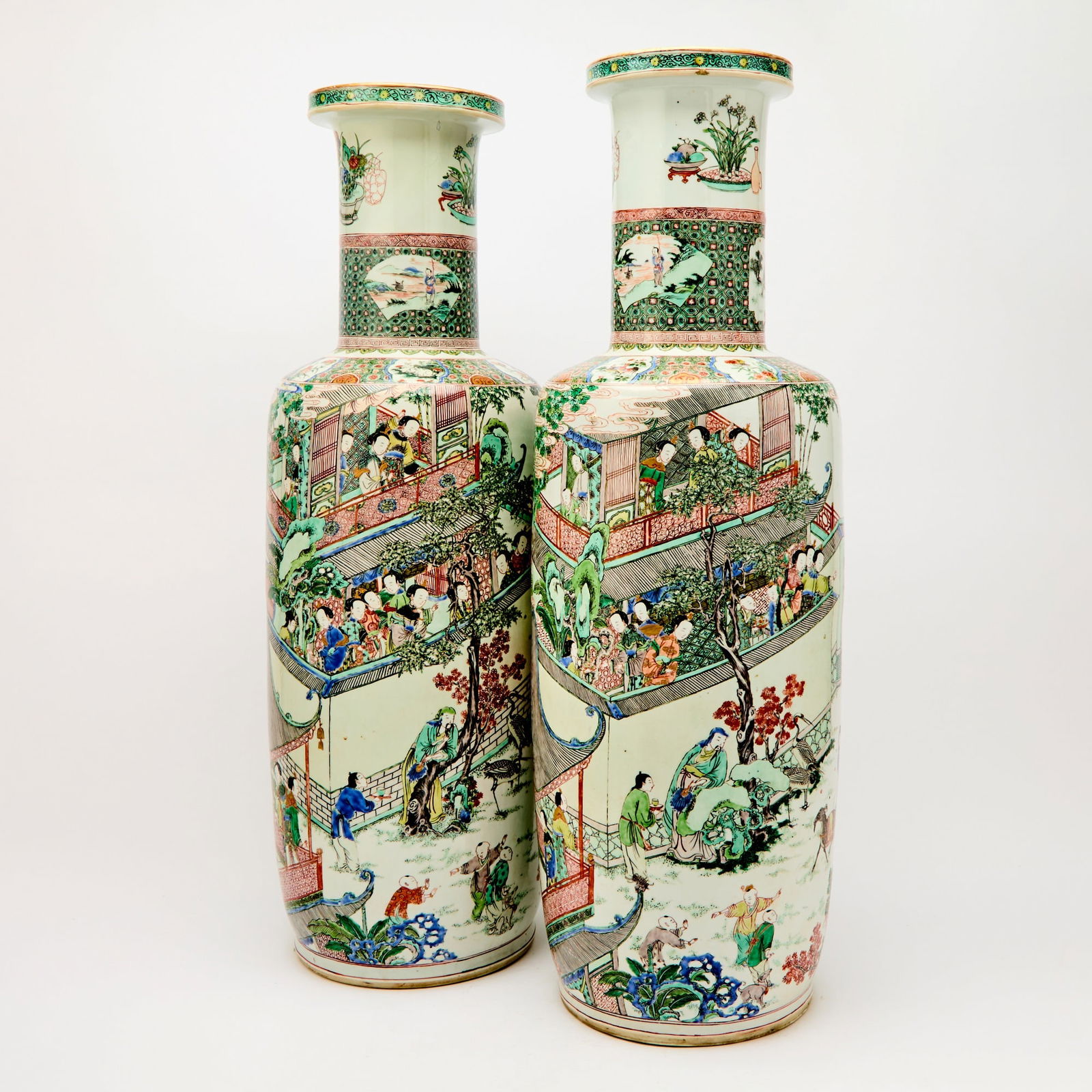A Magnificent Pair of Chinese Famille Verte Porcelain Rouleau Vases Kangxi Period: The exterior body is decorated with a continuous figural scene depicting Pan Yue riding in a carriage drawn by rams and attended by servants. Crowds line the roadside and gather within halls and pavil