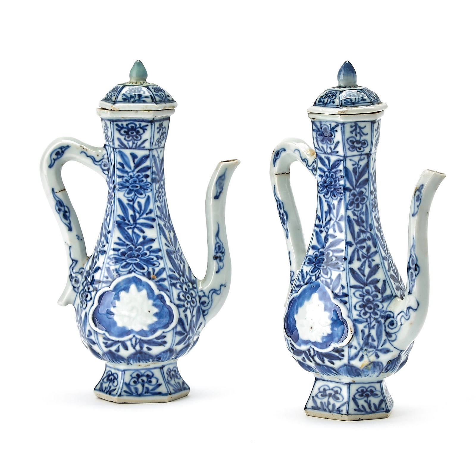 A Pair of Chinese Blue and White Porcelain Ewers Kangxi Period: Each of hexagonal form, the body decorated with raised medallions enclosing lotus blossoms, reserved within panels of blossoms borne on leafy branches. (Height 7 inches) Both ewers bearing labels of C