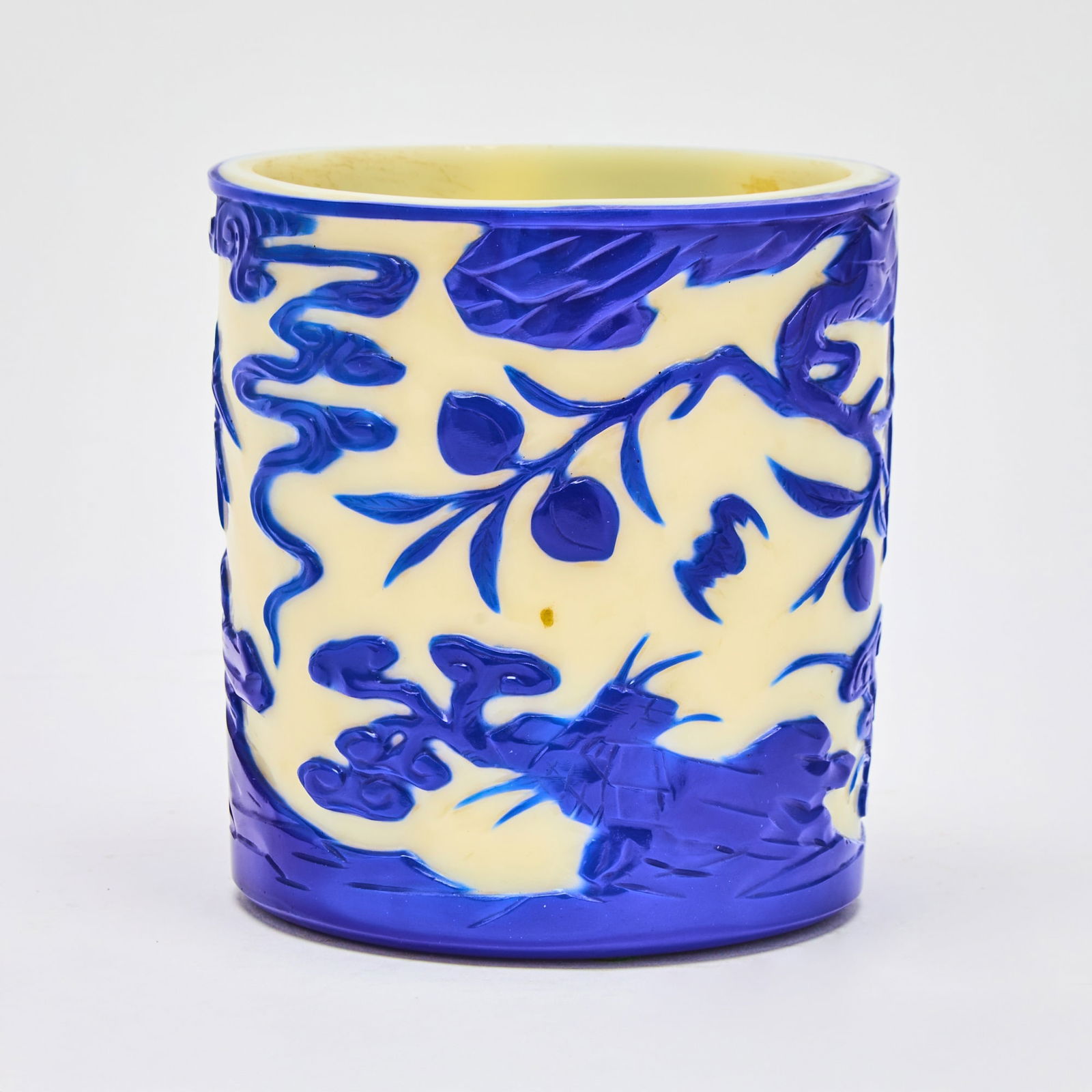 A Chinese Blue Overlay White Glass Brush Pot, Bitong Qianlong Nian Zhi Mark and of the Period: Of cylindrical form; decorated with bamboo, peaches, and lingzhi issuing from rockwork, with bats in flight amidst the scene, all below billowing cloud scrolls. (Height 4 7/8 inches) Chait Galleries,
