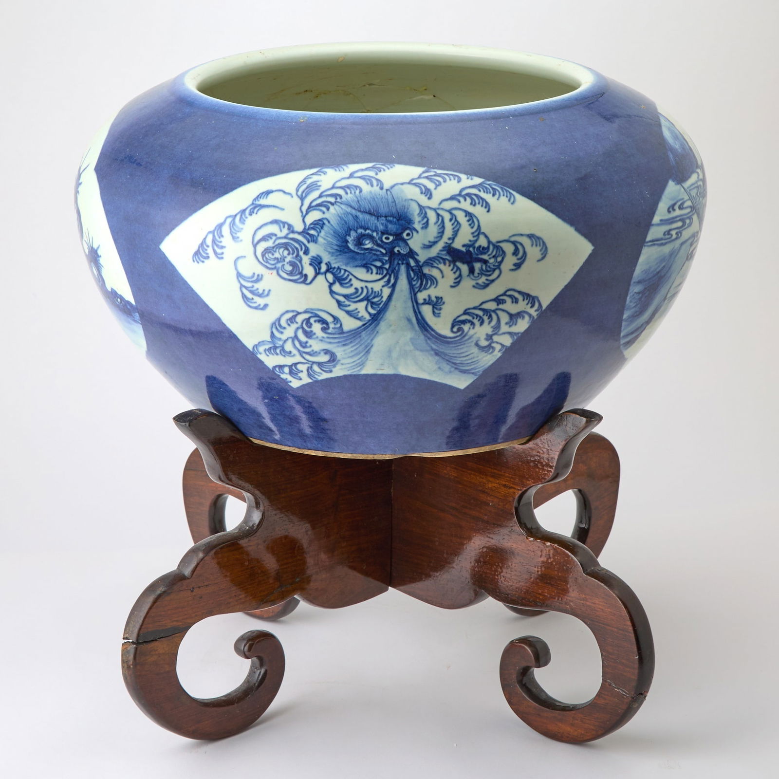 A Chinese Blue and White Porcelain Planter Qing Dynasty: Of bulbous form; decorated with shaped cartouches depicting figures in landscape settings, all reserved against a dark navy-blue ground. (Diameter 19 1/2 inches)