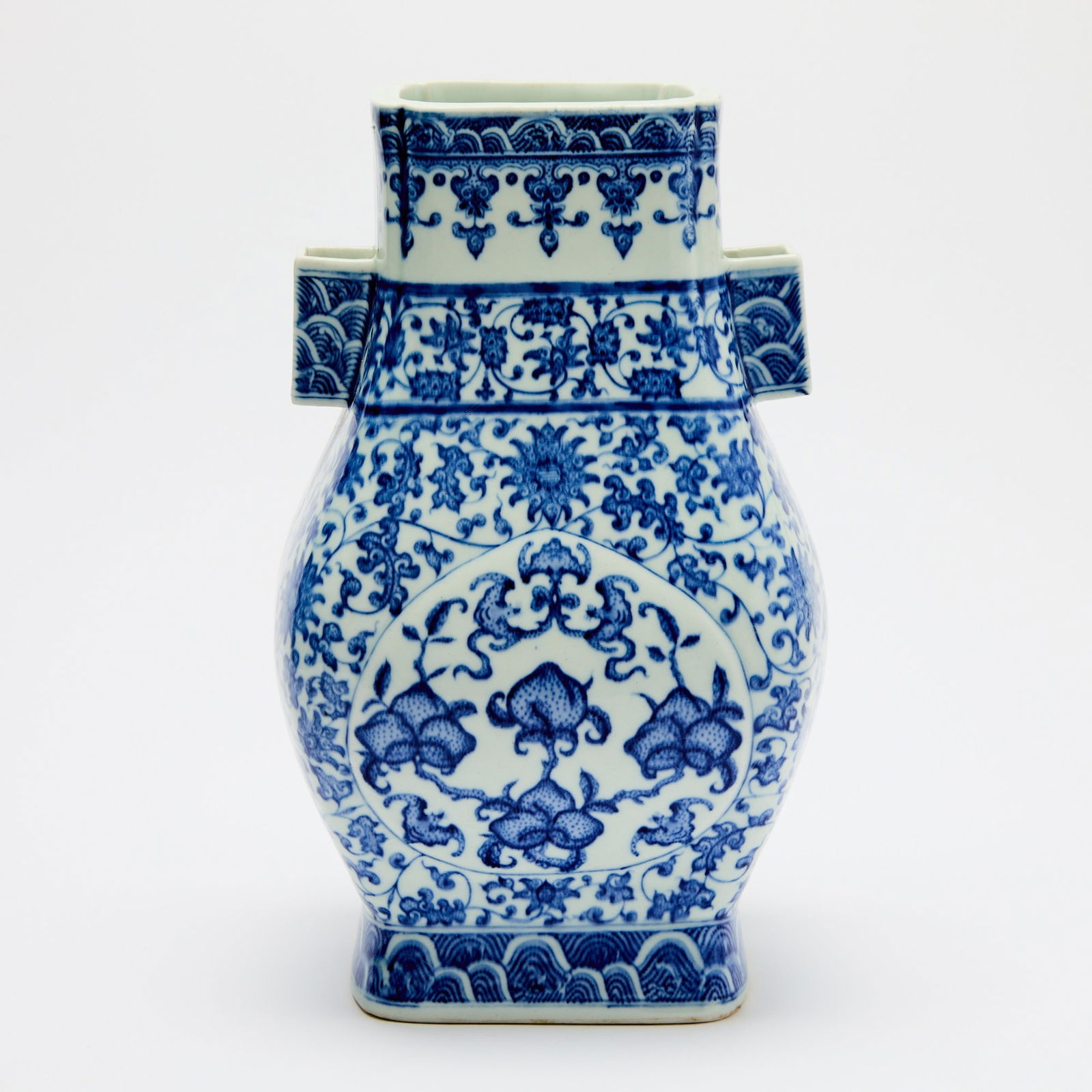 A Chinese Blue and White Porcelain Hu Vase Qianlong Mark, 19th Century: Of rectangular, faceted form with a pair of straight-sided handles; decorated with bunches of peaches borne on scrolling leafy branches surrounded by fu bats, all framed within peach-shaped panels res