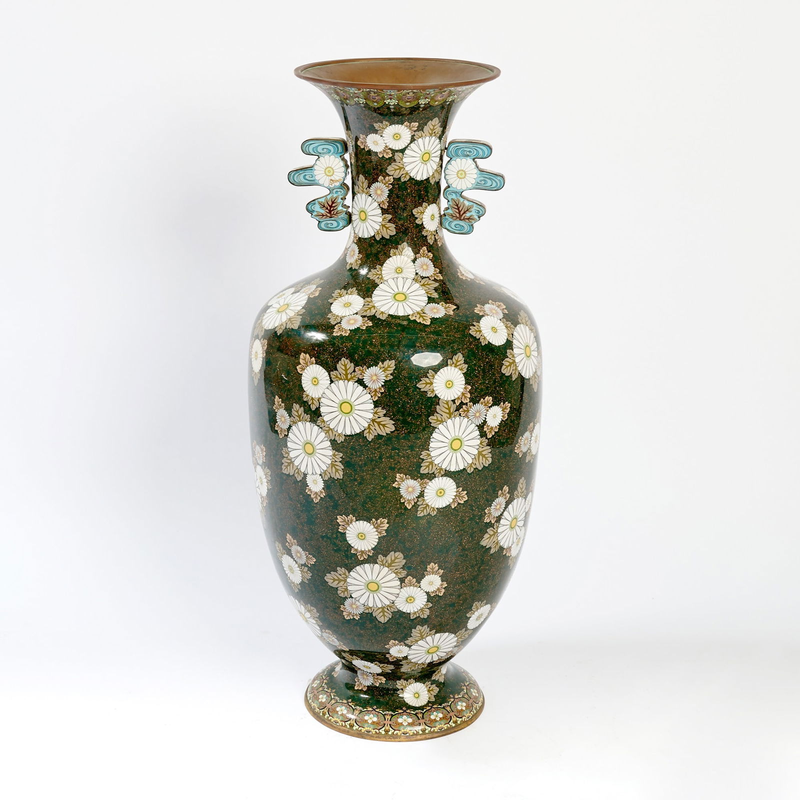 A Large and Exceptional Japanese Cloisonne Enamel Vase Meiji Period: The tapering ovoid vase raised on splayed base and with trumpet neck decorated to show a profusion of white chrysanthemums with cream colored leaves against a gold-flecked greenish-black ground; the n