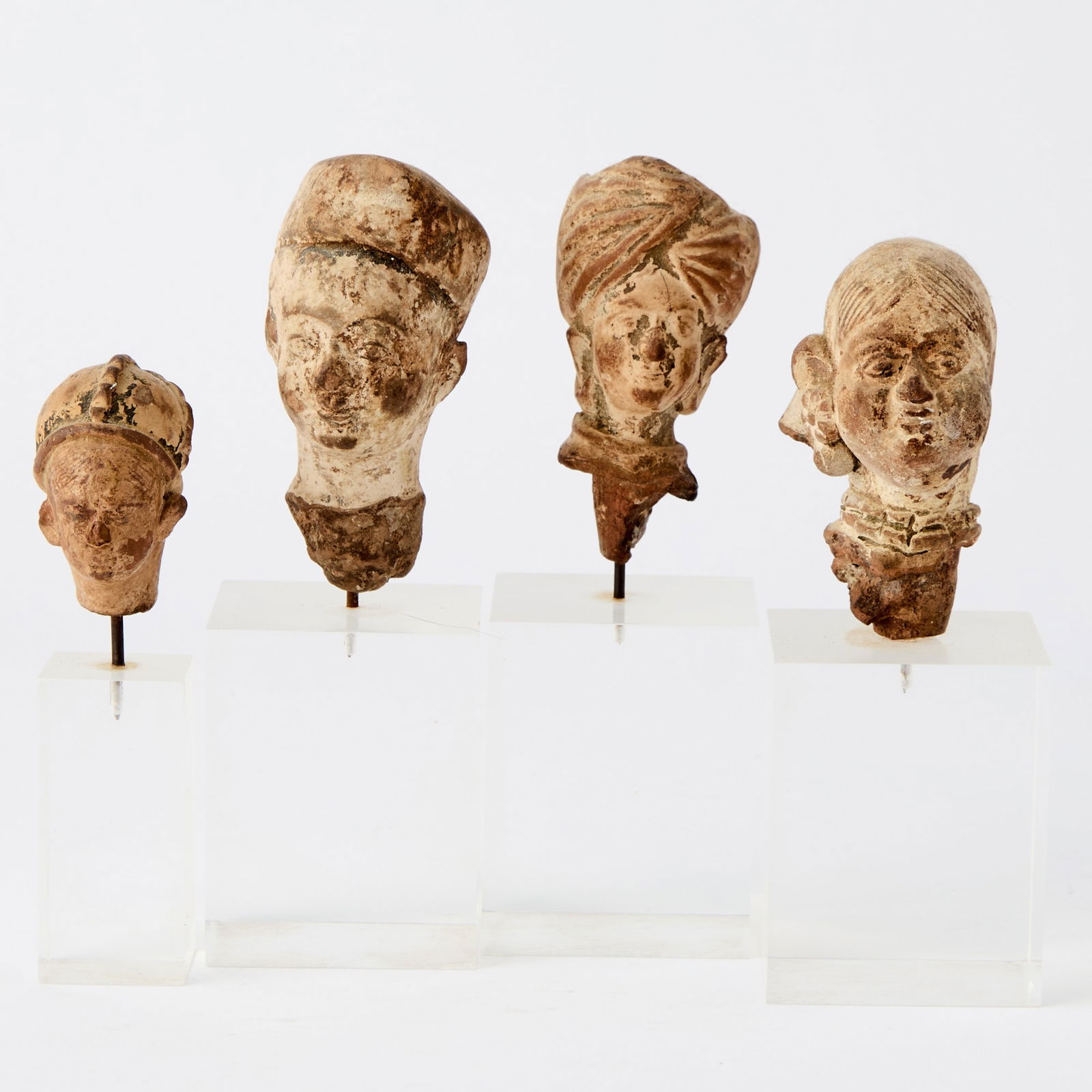 Four Indian Terracotta Heads Possibly Gupta Period and later: Depicting a woman's head and those of three men in headdresses. (Height of tallest pottery 3 1/4 inches)