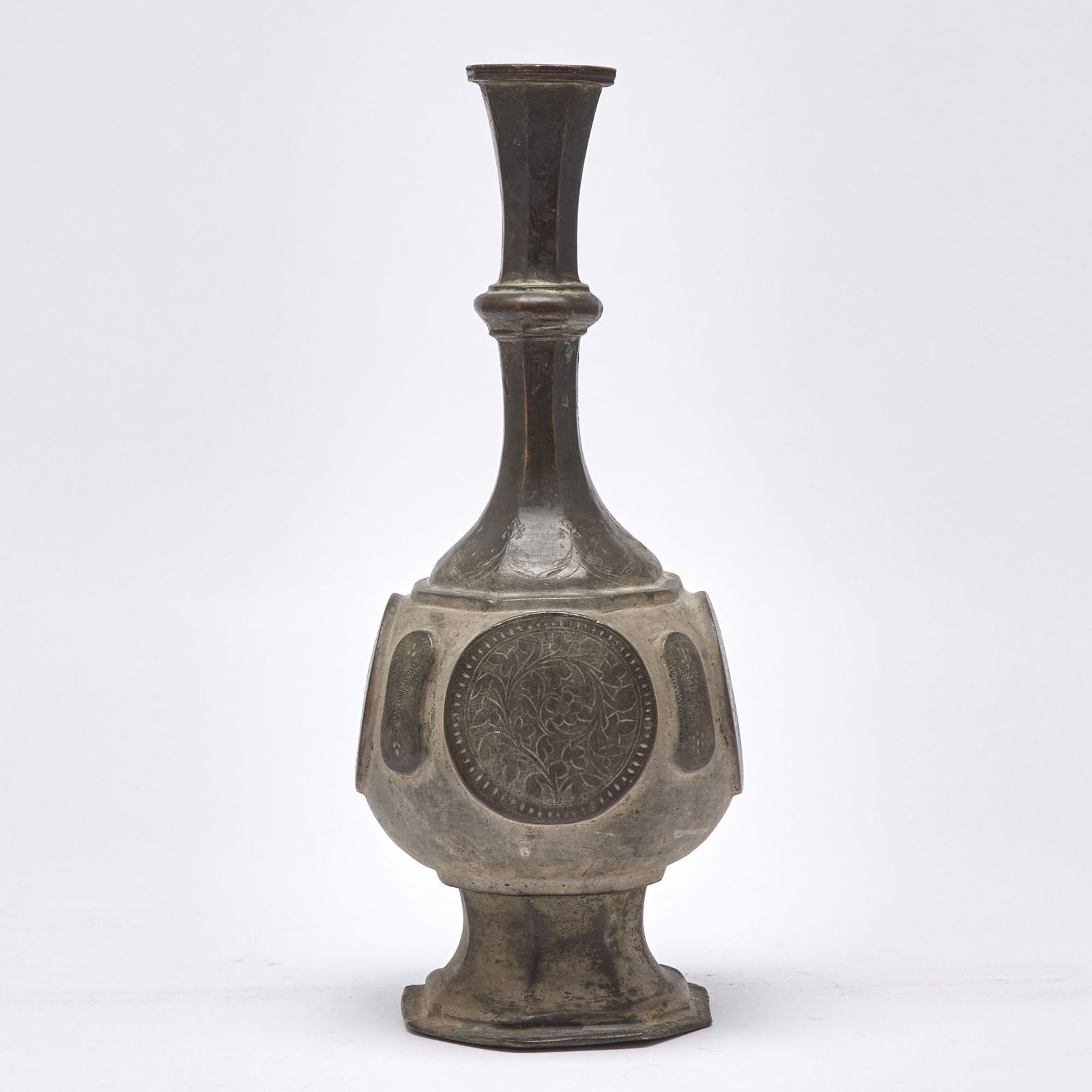 An Indian Bronze Water Bottle Probably Deccan India, 17th-18th century: Raised on faceted, splayed foot, the ovoid body cast with raised and incised floral panels and issuing faceted neck. (Height 13 1/2 inches)