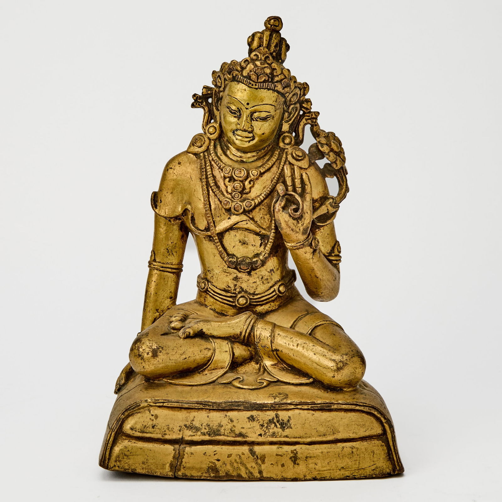 A Tibetan Gilt Bronze Figure of a Bodhisattva 17th/18th Century: The crowned figure cast in dhyanasana atop a cushion base. (Height 9 inches)