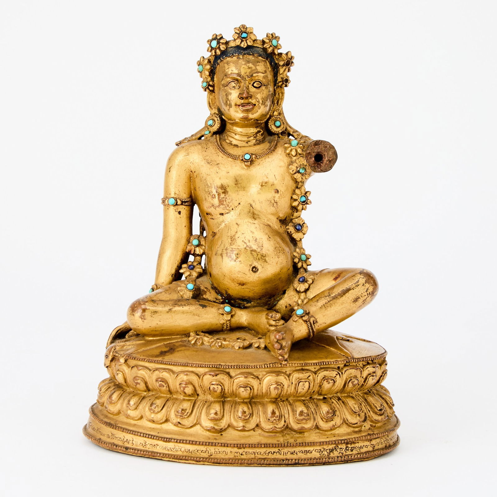 A Rare Tibetan Gilt Bronze Figure of Virupa 16th-17th Century: The corpulent figure sits upon a deer skin atop a double lotus base bearing inscriptions around its circumference and verso; he wears a floral headress and floral garland around his neck set with turq