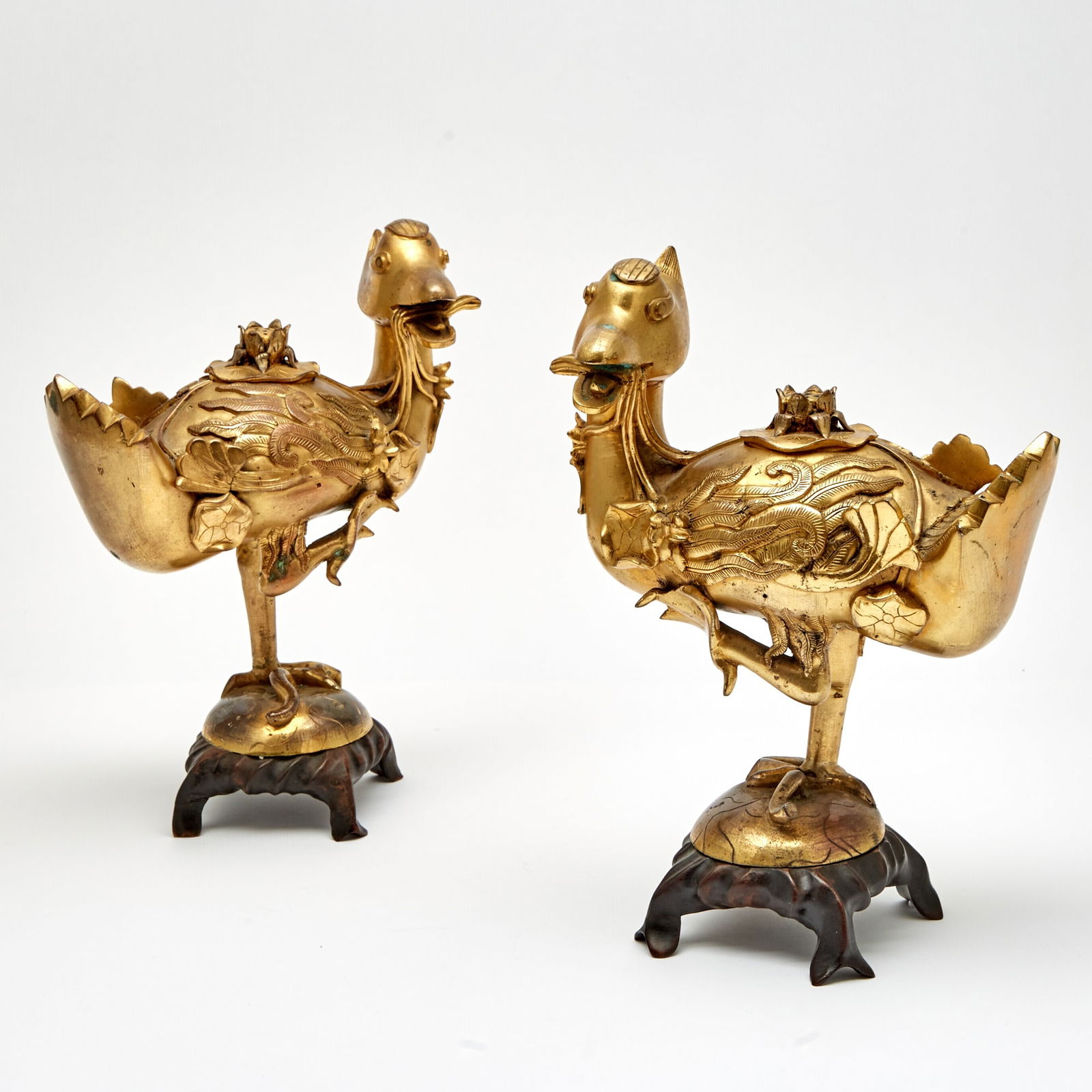 A Mirrored Pair of Chinese Gilt Bronze Figural Censers Qing Dynasty: Each cast as a crane standing on one leg, issuing a lotus stem from its mouth toward the cover surmounted by an opening on its back. (Height of figure 9 1/2 inches)