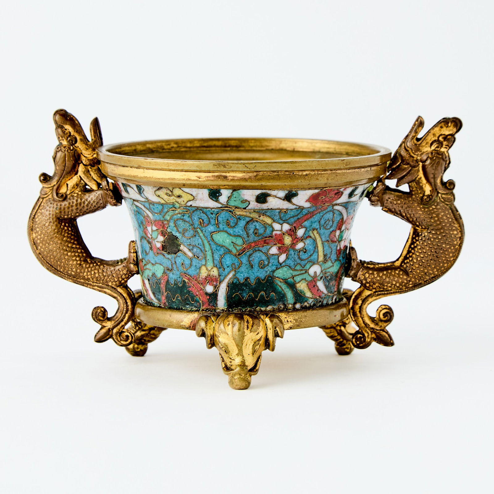 A Chinese Cloisonne Enamel Tripod Censer Jingtai Nian Zhi Mark: Of flaring form, the body supported on three elephant-head legs and flanked by a pair of handles cast in mythical beast form, the exterior decorated with lotus blossoms on scrolling leafy vines. (Widt