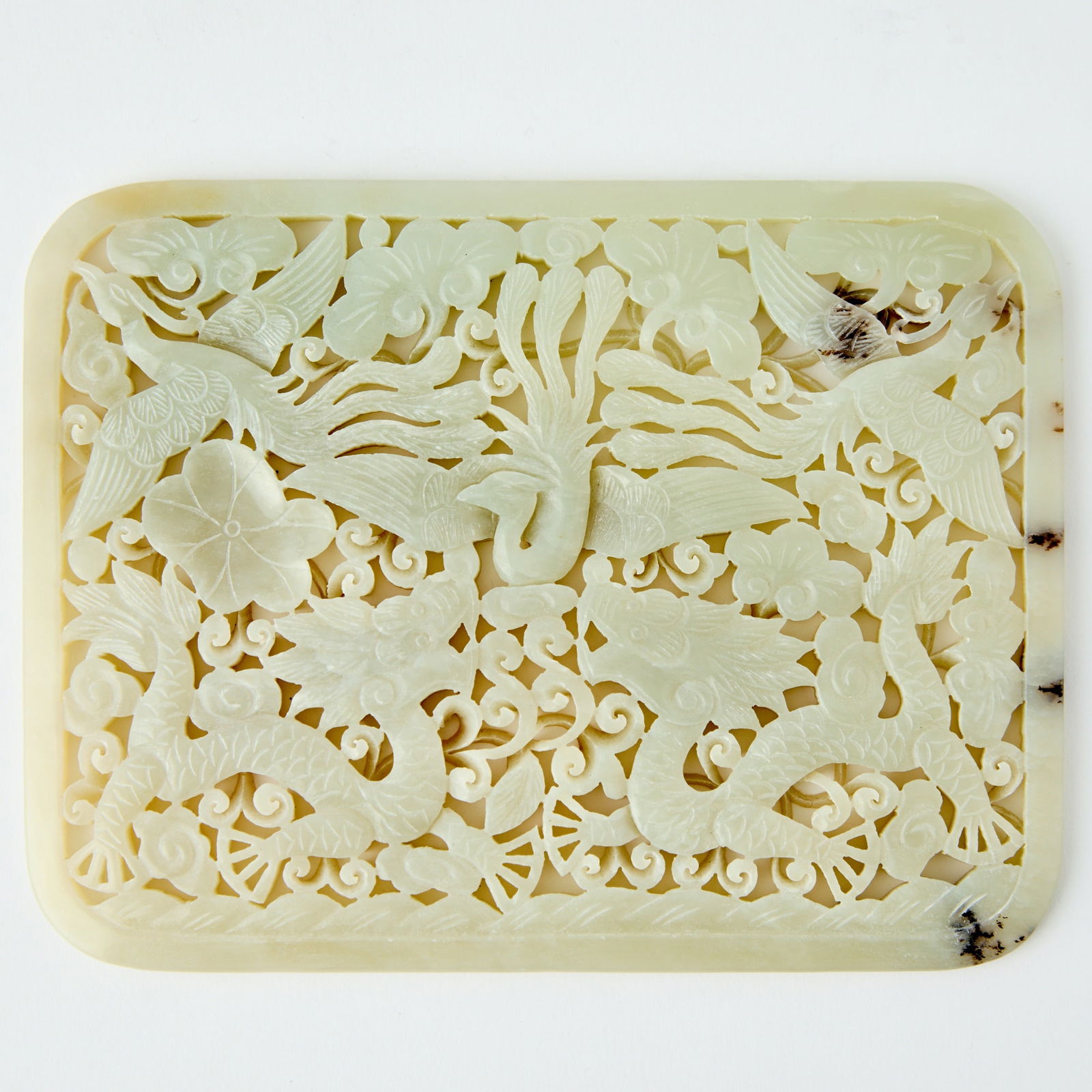 A Chinese 'Dragon and Phoenix' Jade Reticulated Plaque Qing Dynasty or earlier: Of rectangular form with rounded corners, carved in openwork to depict a pair of confronting dragons below three phoenix in flight, amid scrolling foliage and clouds. (Length 5 1/2 inches)
