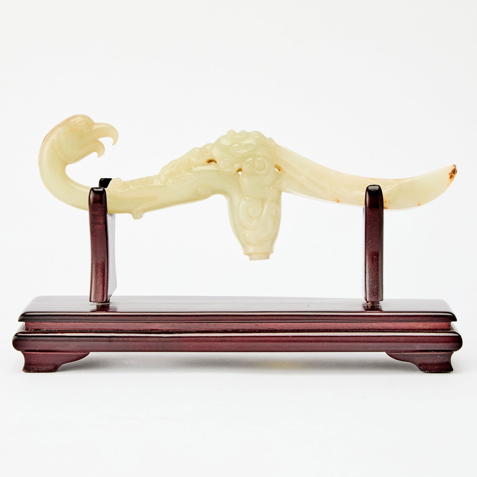 A Chinese Carved Celadon Jade Handle Qing Dynasty: Carved as a bird with a curving body; the stone with russet inclusions. (Length 9 1/4 inches)