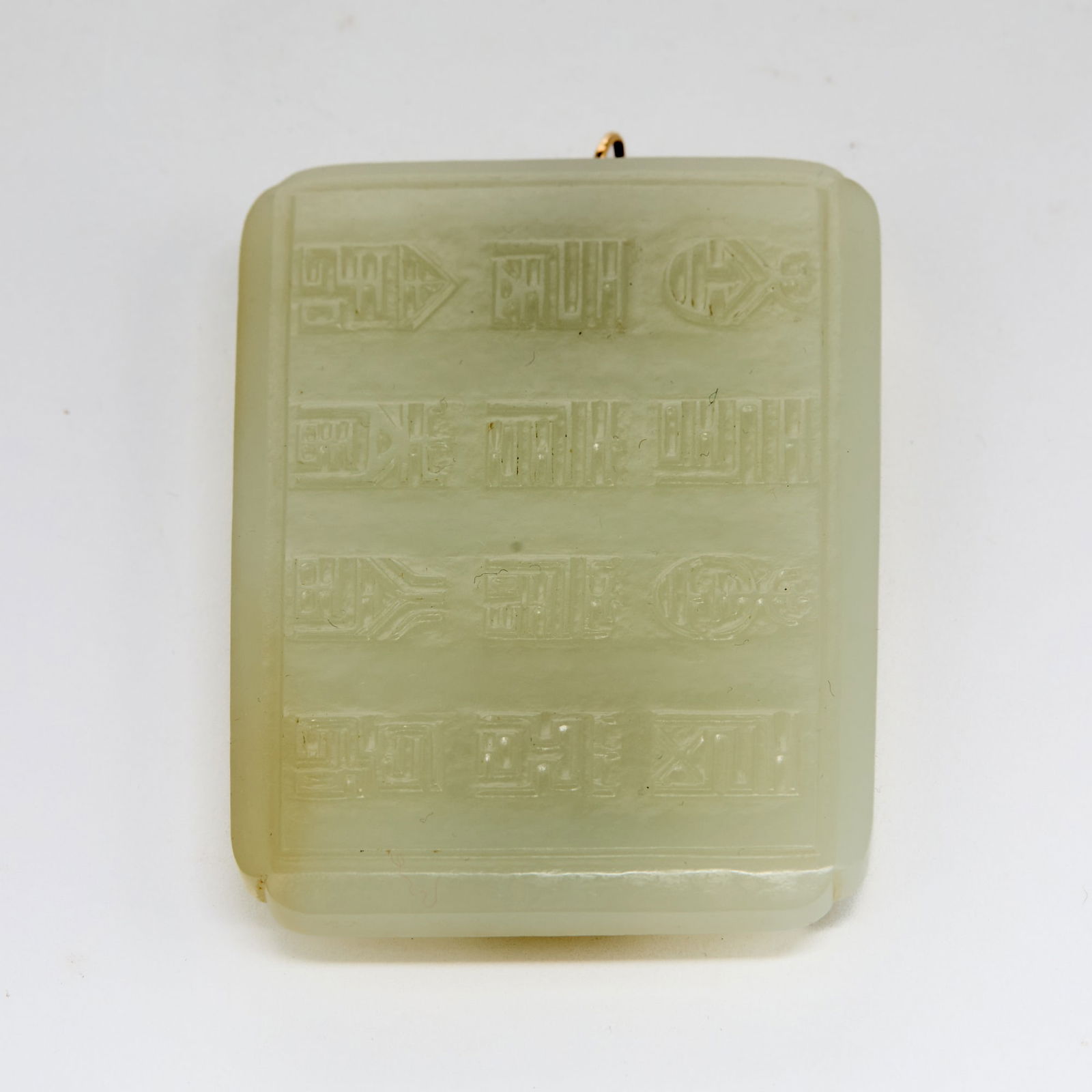 A Chinese Carved White Jade Buckle 18th-19th Century: Of rectangular form; carved with ‘shou’ characters in various styles, the reverse with a raised dragon head and a stud in the form of the bagua. (Length 3 inches)