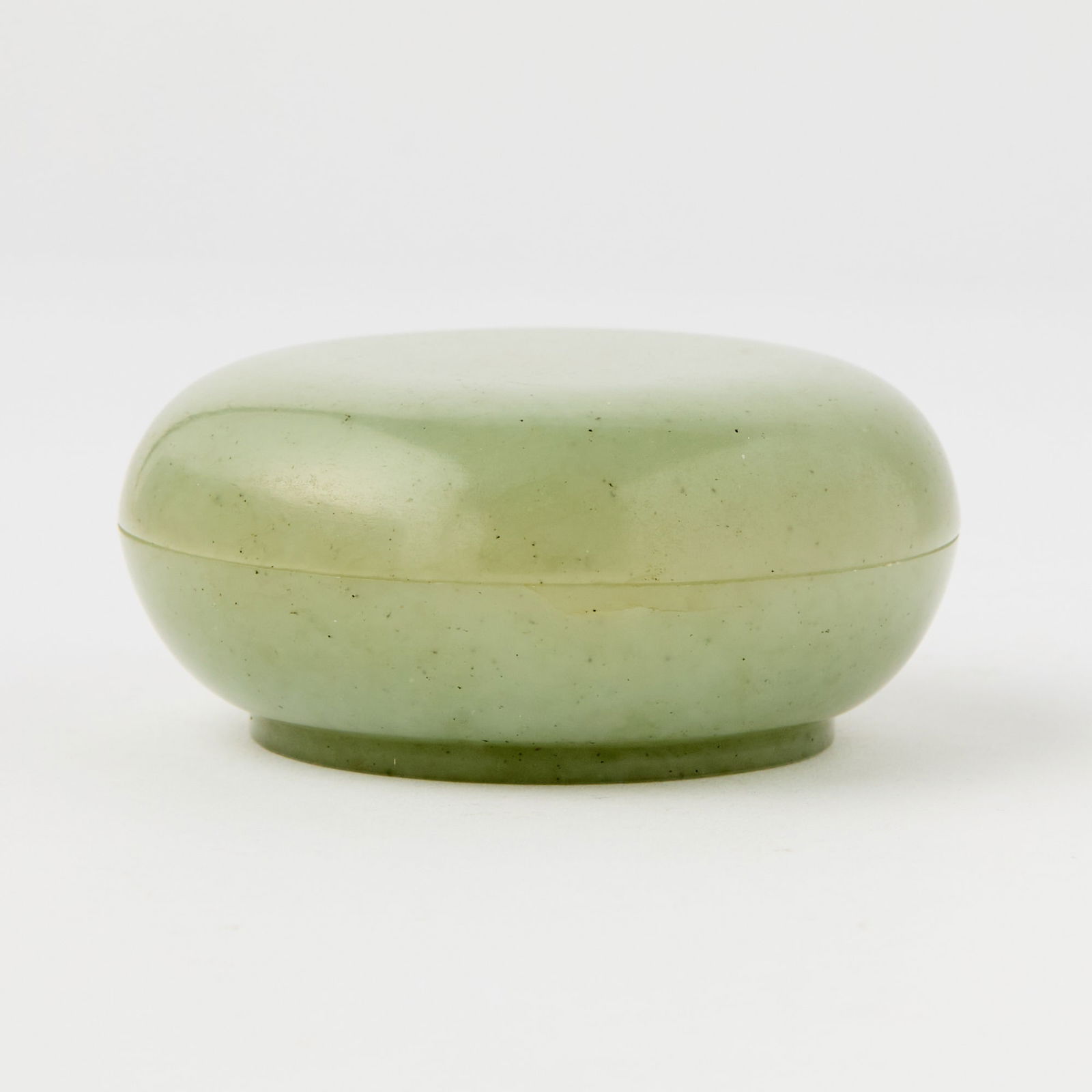 A Chinese Celadon Jade Covered Box Qing Dynasty: Of circular domed form; the stone with some black speckles. (Diameter 3 inches)Qty: (2)