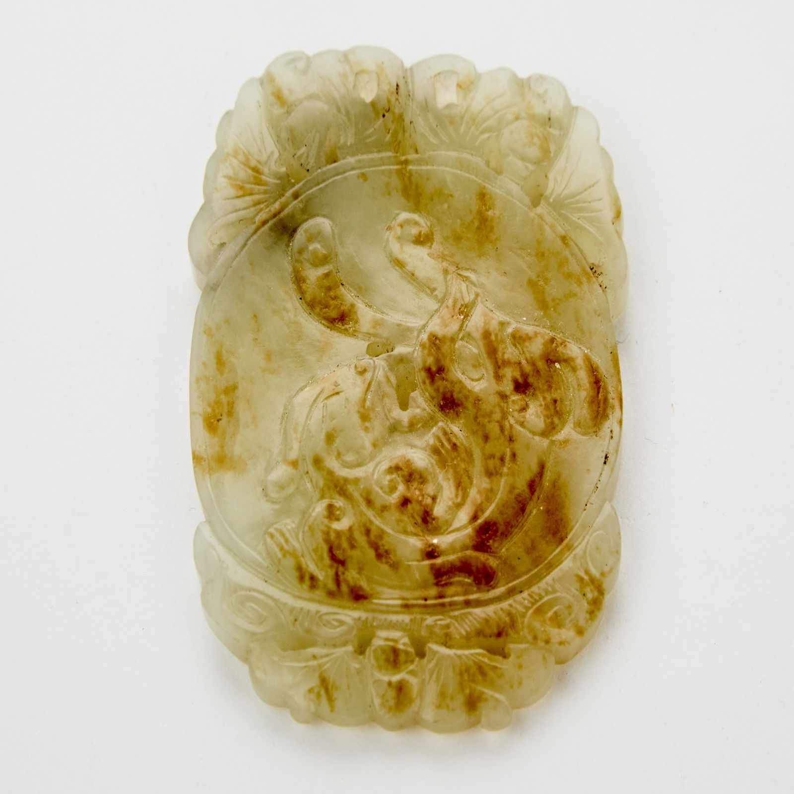 A Chinese Pebbled White Jade Oval Plaque 19th Century: Carved to show a qilong to face and verso with a millet-patterned bi disc. (Length 3 inches)
