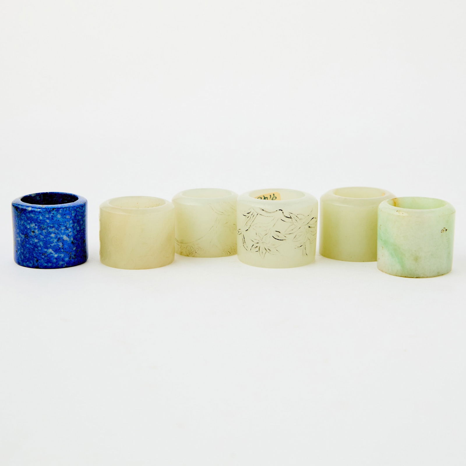 Six Chinese Hardstone Thumb Rings Qing Dynasty: Comprising four jade, one jadeite, and a lapis lazuli example. (Height of largest 1 inch)