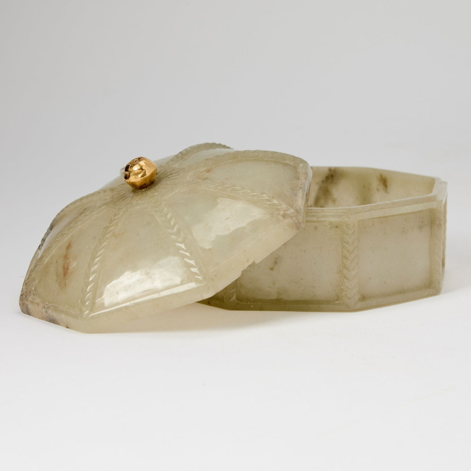 A Mughal Indian Jade Octagonal Pandan Box and Cover Likely 18th century: The cover carved with a central flower at top issuing chevron bands at corners, surmounted by a high-carat gold knop incised with a floral motif, the box similarly decorated, the base with petals issu