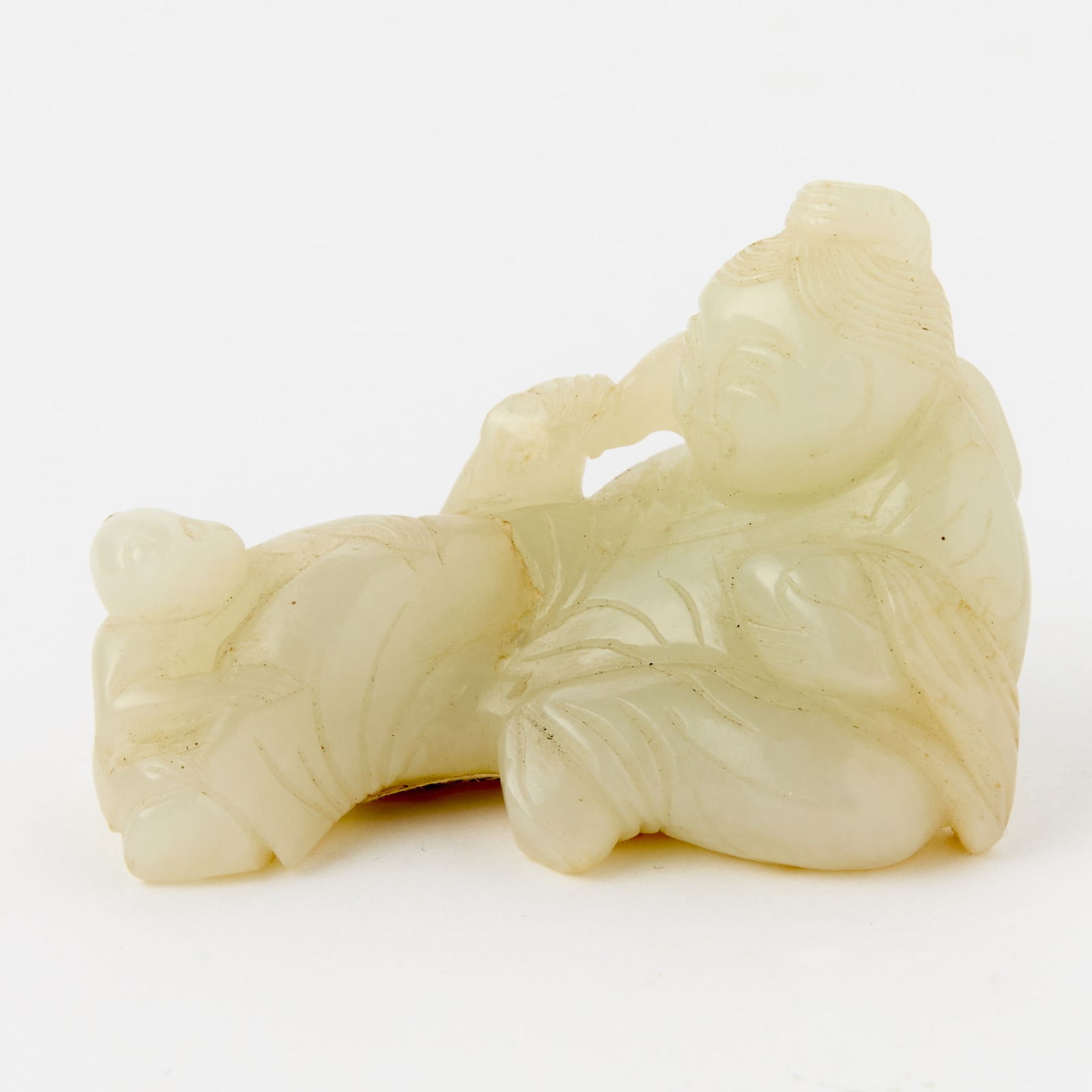 A Chinese White Jade Figural Carving 18th-19th Century: Carved as a reclining figure with a baby monkey clinging to his leg. (Length 2 1/2 inches)