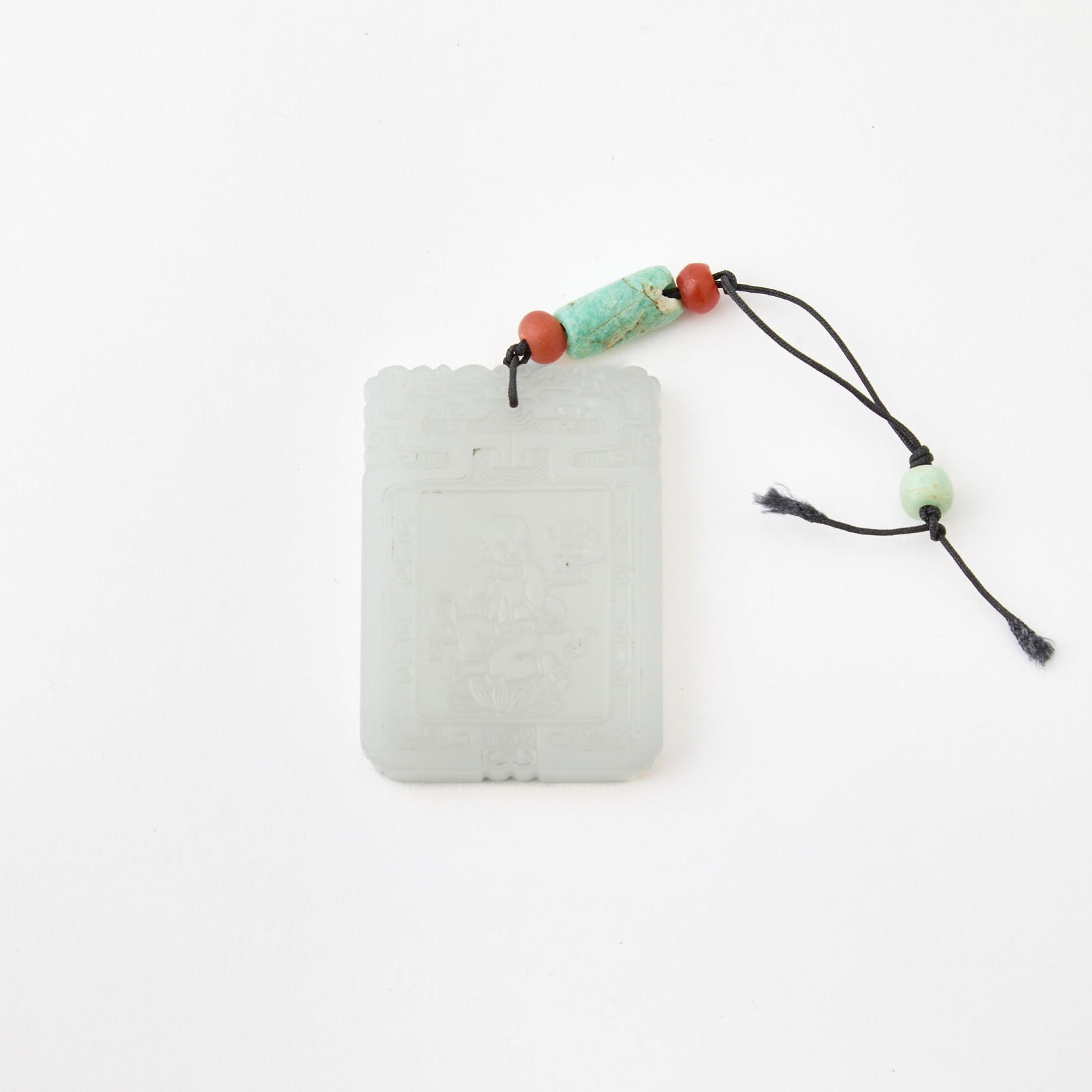 A Chinese White Jade Plaque 18th century: Carved in low relief with a boy seated on a lotus blossom, framed by a pair of confronted dragons holding a pearl in their mouths; the reverse with a similar border enclosing a ‘Yongzheng nian z