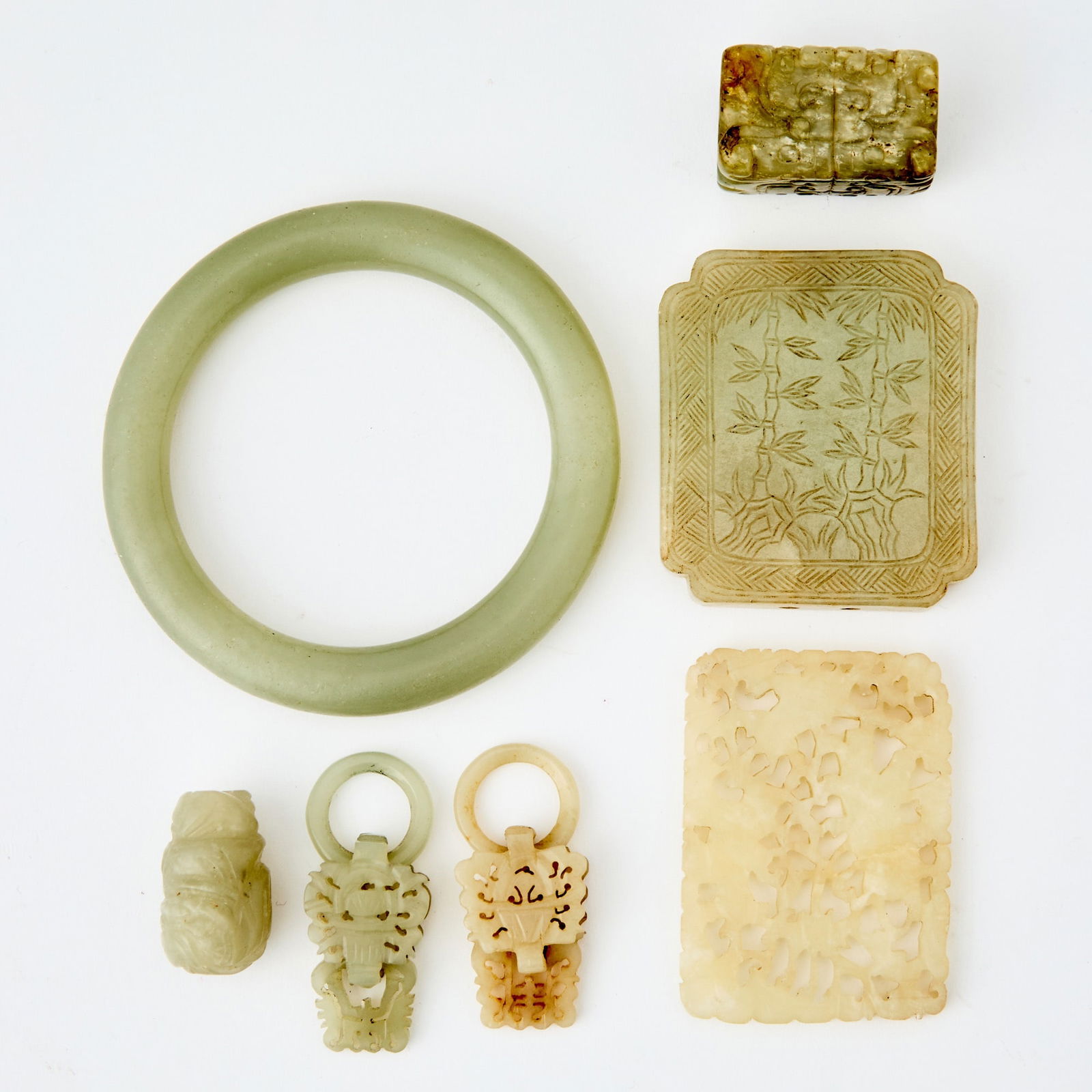 Seven Chinese Carved Jade Articles 19th Century: Comprising a bangle, an openwork plaque, a plaque with low-relief decoration, an archaistic bead, a figural bead, and two rings with openwork decoration. (Diameter of bracelet 3 inches)