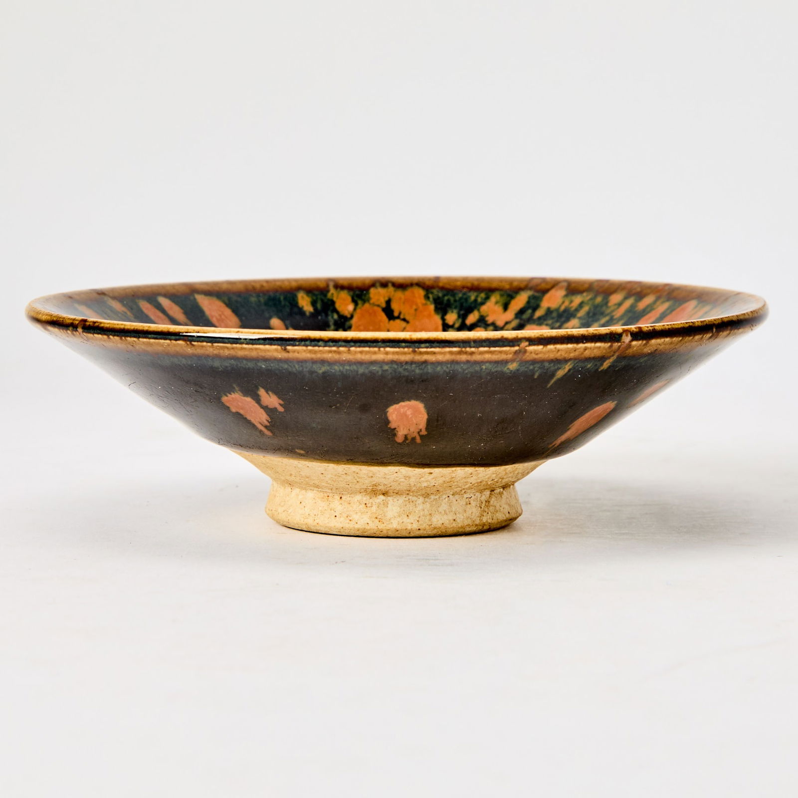 A Chinese Cizhou Type 'Partridge Feather' Bowl Song to Jin Dynasty: Of shallow conical form; decorated with russet splashes over a black ground. (Diameter 5 1/2 inches)