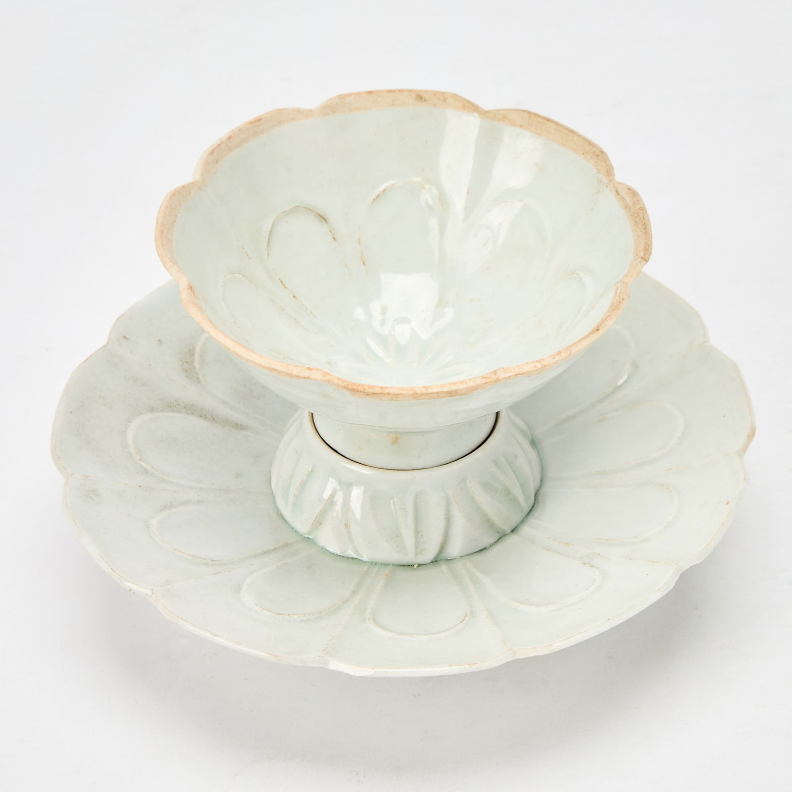 A Chinese Qingbai Molded Cup and Stand Song Dynasty or later: The cup and saucer both molded with flower petal textures and petal rims. (Diameter of stand 5 3/4 inches)