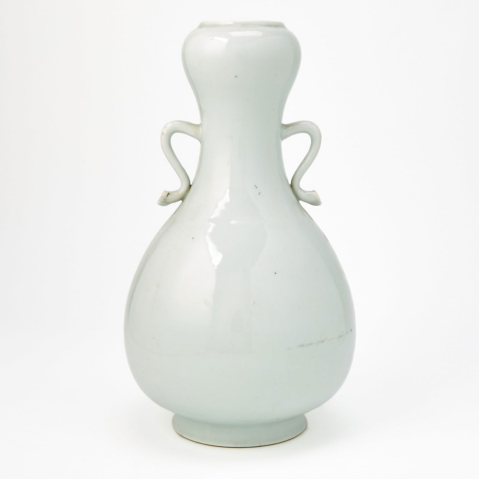 A Chinese White Glazed Porcelain Garlic-Head Vase 18th-19th century: Of pear form, the body flanked by a pair of S-shaped handles terminating in ruyi heads. (Height 13 1/4 inches)