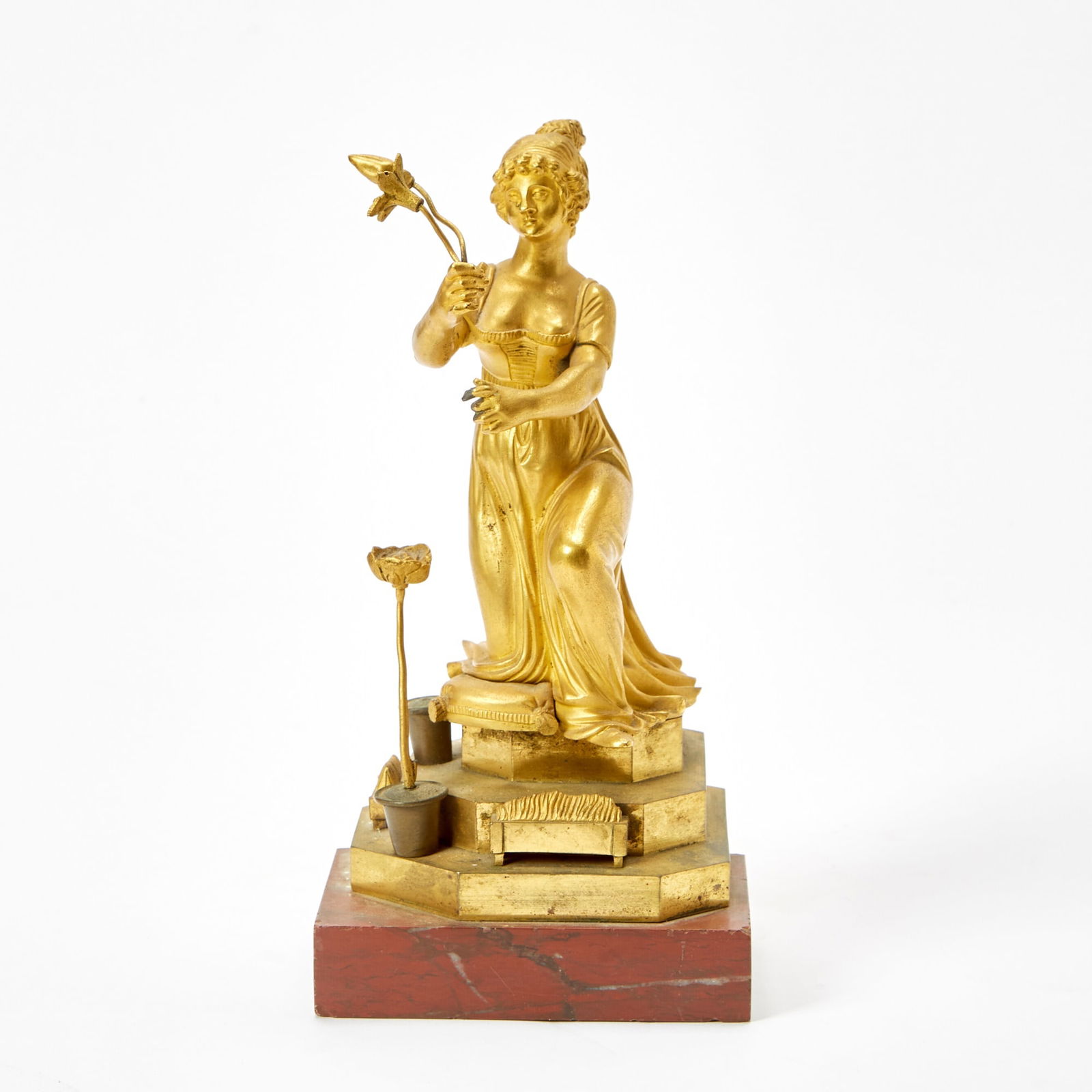 French Gilt-Bronze Figure of a Woman Holding a Floral Sprig: 19th CenturyRaised on a marble base. Height of bronze 9 inches, width 4 1/2 inches. rubbing to bronze; marble base broken as seen in photograph
