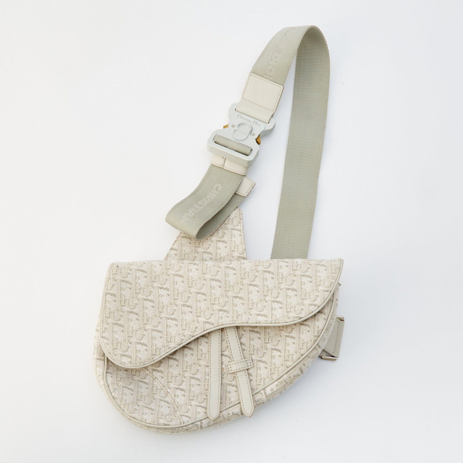 Christian Dior Canvas and Leather Saddle Crossbody Bag: Printed canvas with white leather trim, front flap and zip-top opening, wide crossbody strap, signed Dior. 10 3/4 x 7 1/4 x 1 3/4 inches. Light wear. Minor creasing to leather.