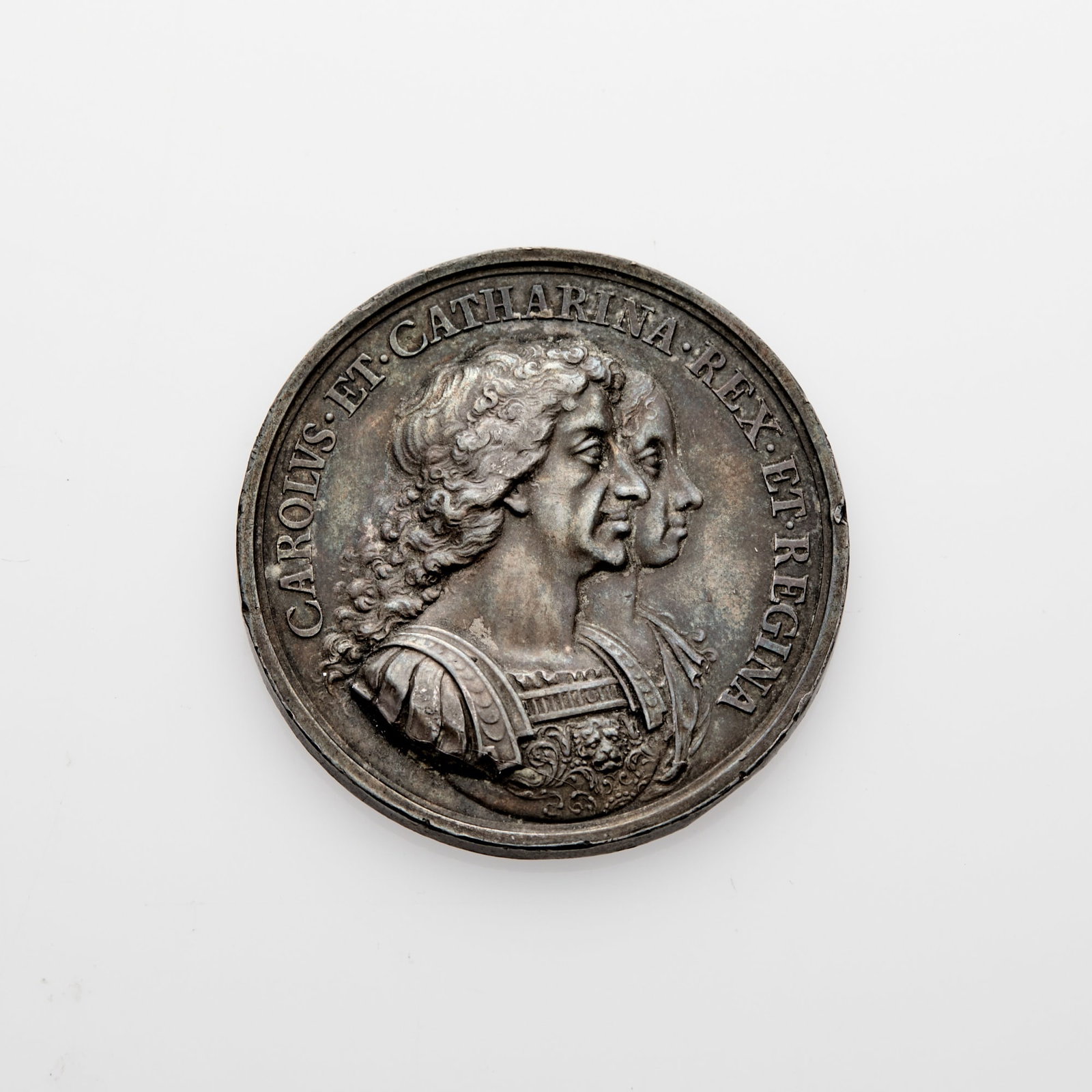 Great Britain. 1670 Colonization Silver Medal. 41mm. 33.26g. Uncirculated, Minor Marks.: A few rim hits do not distract from the pretty, even gray coloration with subtle pastel toning. OBV: Conjoined busts of King Charles II and his wife Catherine of Braganza, surrounded by text reading "