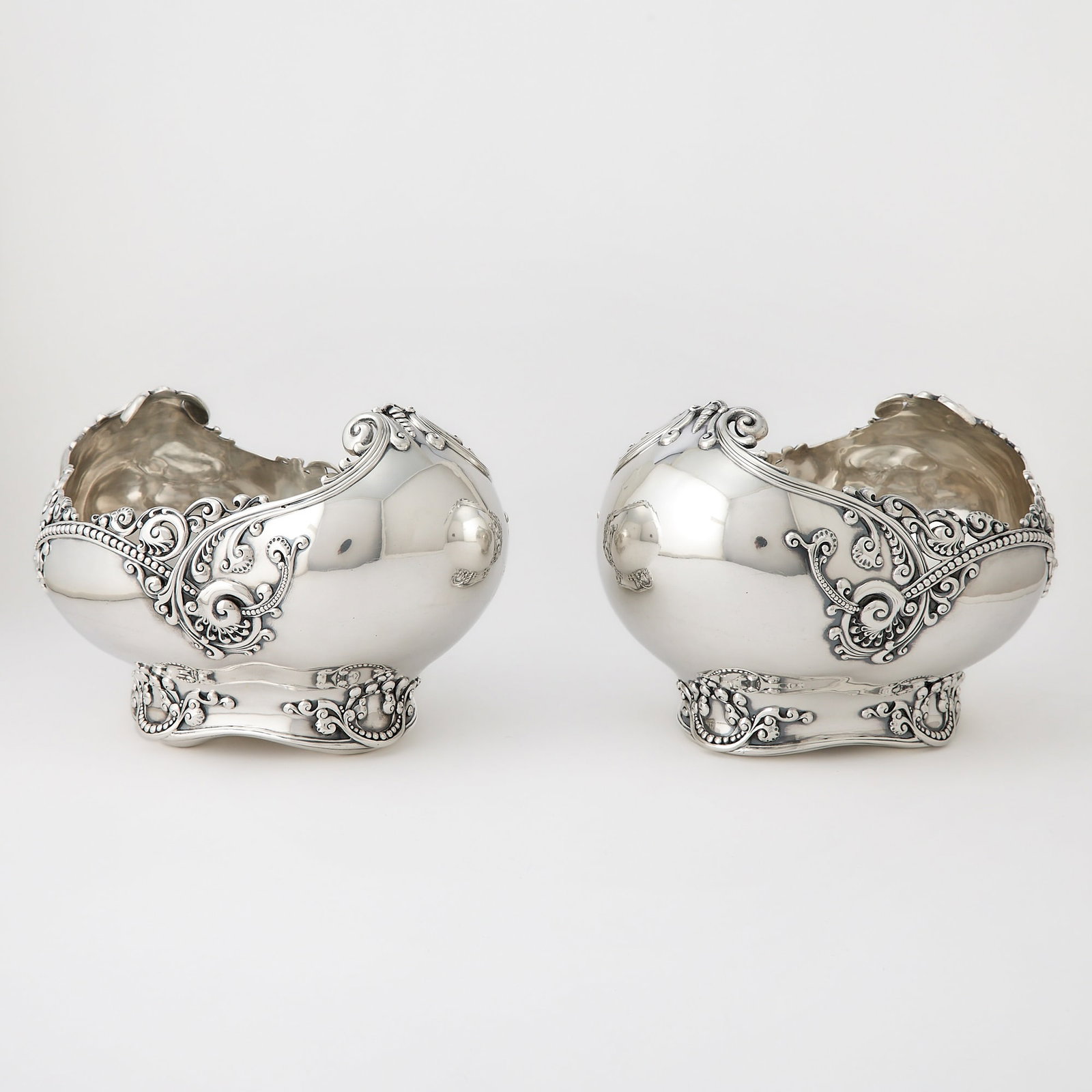 Pair of Tiffany & Co. Sterling Silver Centerpiece Bowls: 1892-1902 Oval with scrolling ends, applied with pearling and foliate scrolls. Height 8 inches, length 12 inches, total approximately 132 ounces. Generally good condition overall with light wear as e
