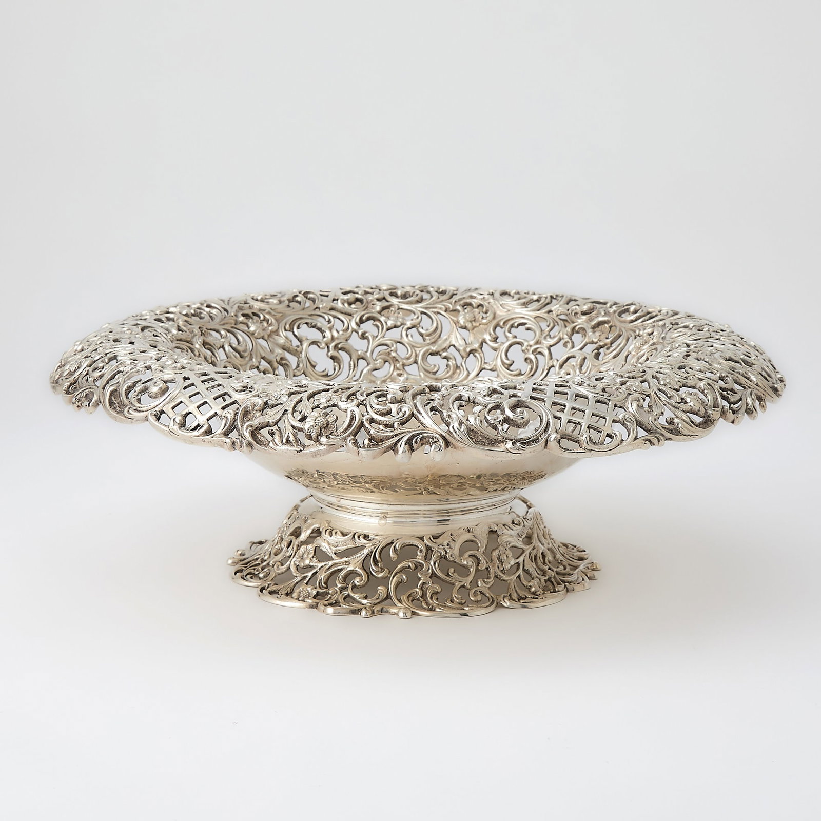 J.E. Caldwell Sterling Silver Footed Centerpiece Bowl: Early 20th century The circular body engraved with foliate scrolls, the everted rim pierced with lattice and foliate scrolls. Height 4 1/4 inches, diameter 12 1/2 inches, approximately 49 ounces. Gen