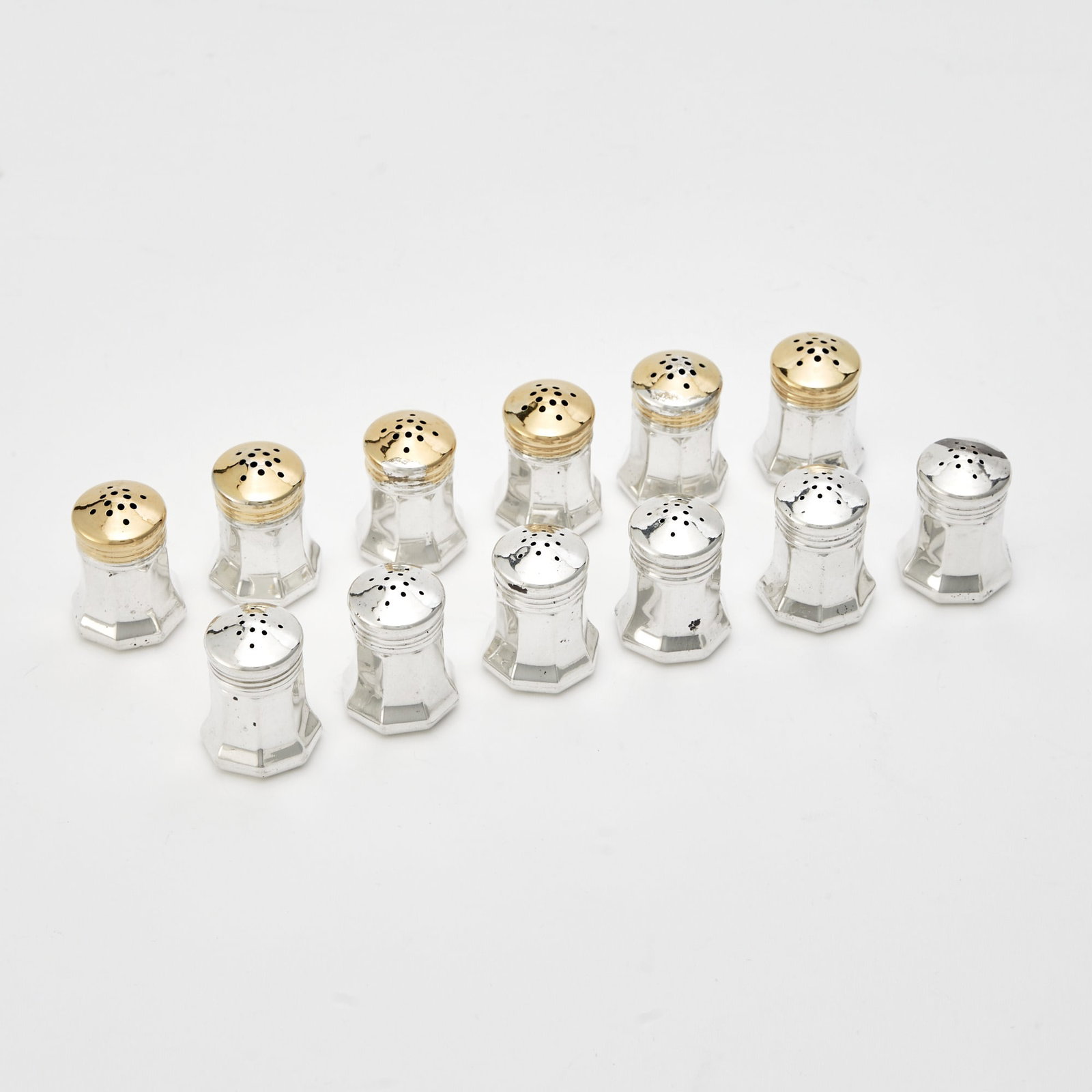 Set of Twelve Cartier Sterling Silver Individual Salt and Pepper Casters: Mid 20th century Six with gilt tops. Heights 1 3/8 inches, total approximately 3 ounces. Generally good condition overall; some of the tops rather loose fitting