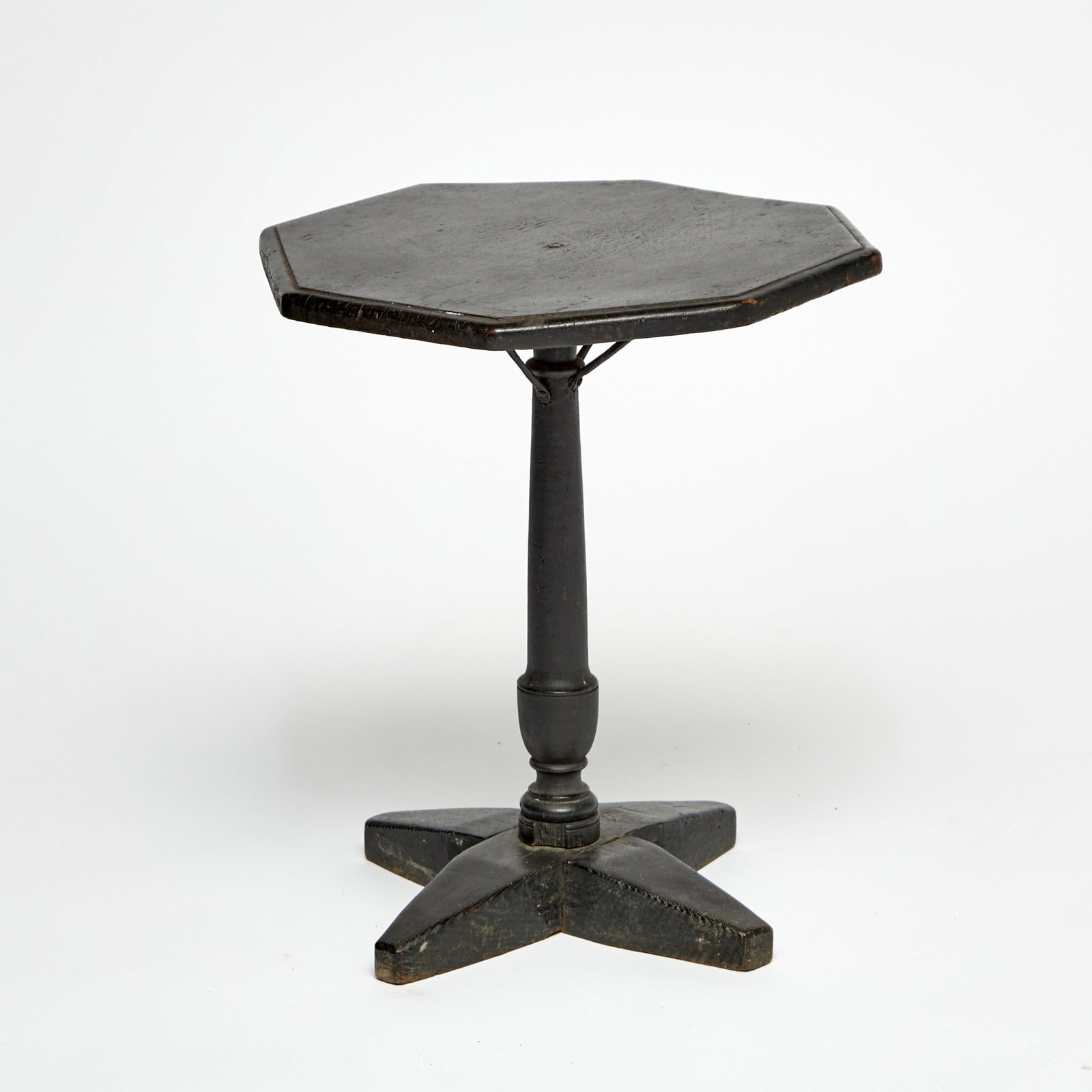 Black Painted Cross-Base Candlestand: Probably New England, early 18th century The octagonal top on a turned post with tapered cross-base. Height 22 1/2 inches, diameter 20 1/2 inches. with three iron supports to underside of top; cracks