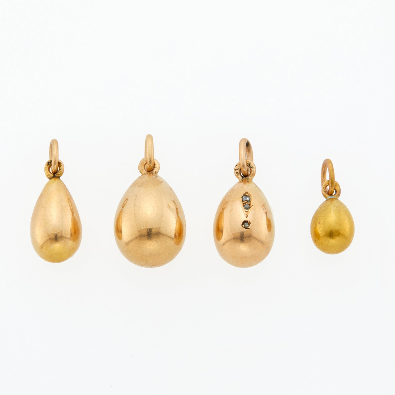 Group of Four Russian Gold or Silver-Gilt Pendant Eggs: Indistinctly marked Each ovoid, one set with three gemstones. Height of largest 9/16 inch (1.43 cm).