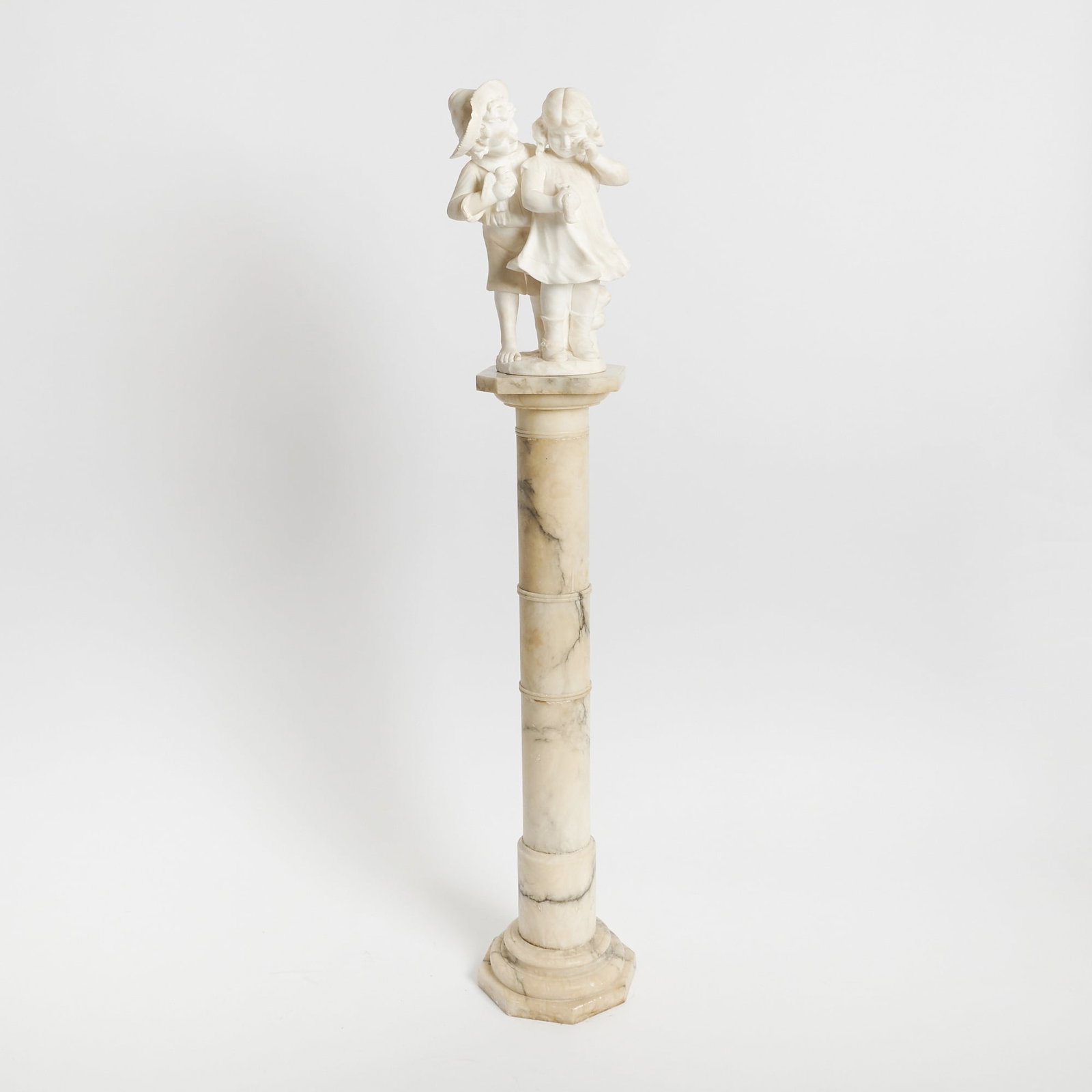 Italian Alabaster Group of a Young Boy and Girl: Early 20th century Height 17 1/2 inches. Together with an Alabaster Pedestal; height 42 1/2 inches, diameter of top 10 3/4 inches.