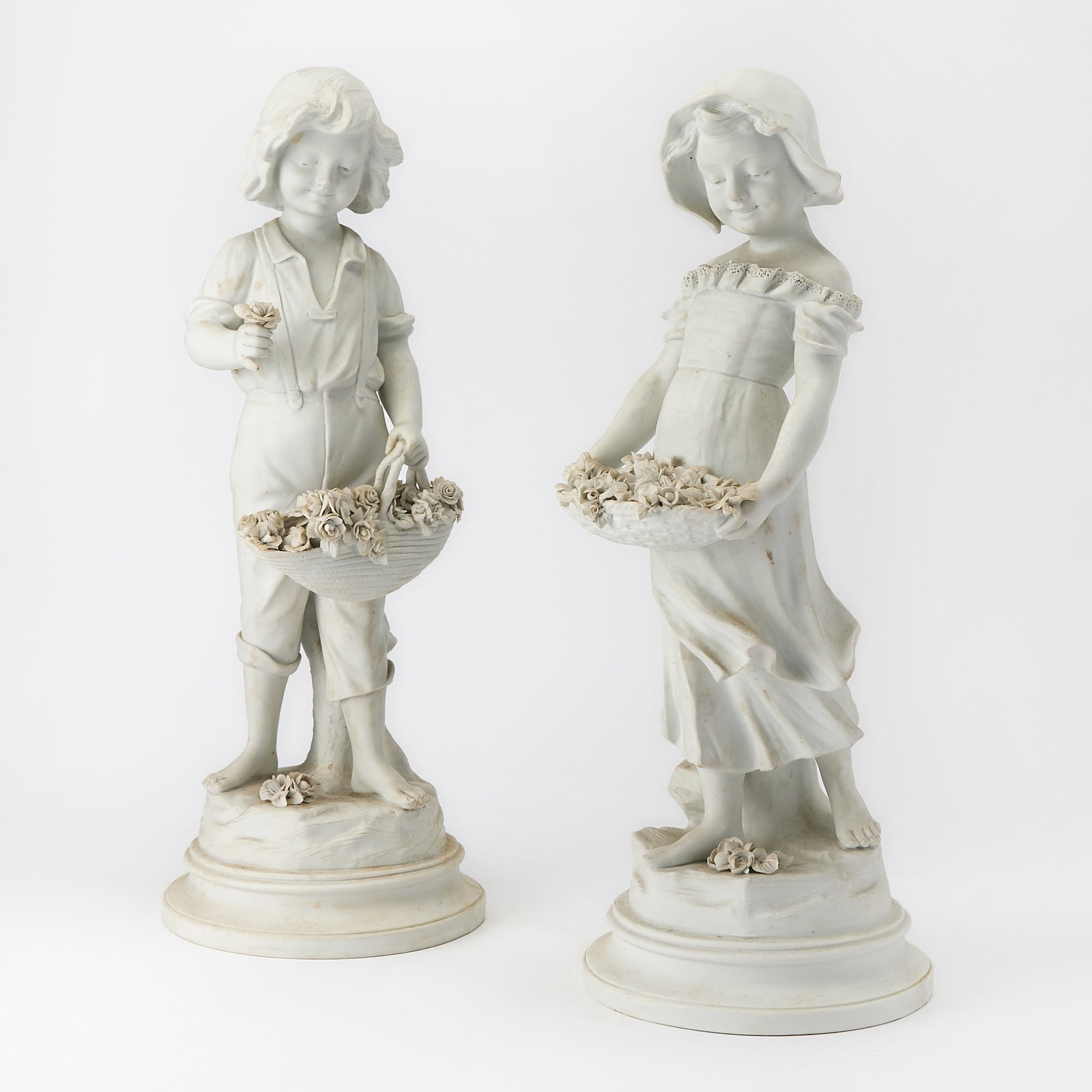 Pair of French Bisque Figures of a Boy and Girl with Flower Baskets: After A. RanieriHeight 20 3/4 inches.