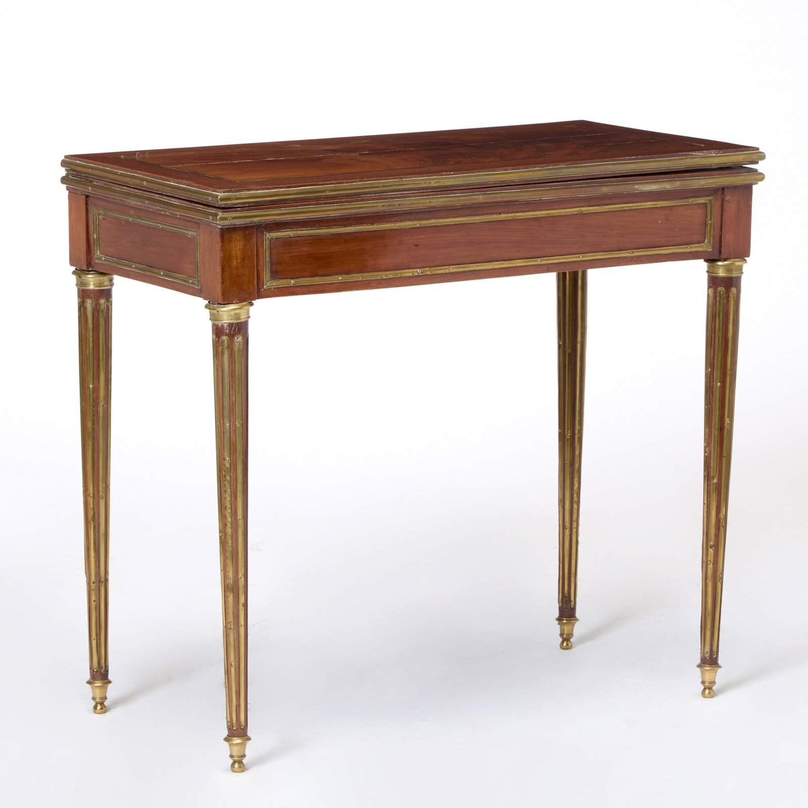 Baltic Neoclassical Brass-Mounted Mahogany Fold-Over Games Table: First half 19th centuryWith a rectangular hinged top, raised on fluted legs. Height 30 1/2 inches, width 34 inches, depth 17 inches some brass moldings dented and distressed.