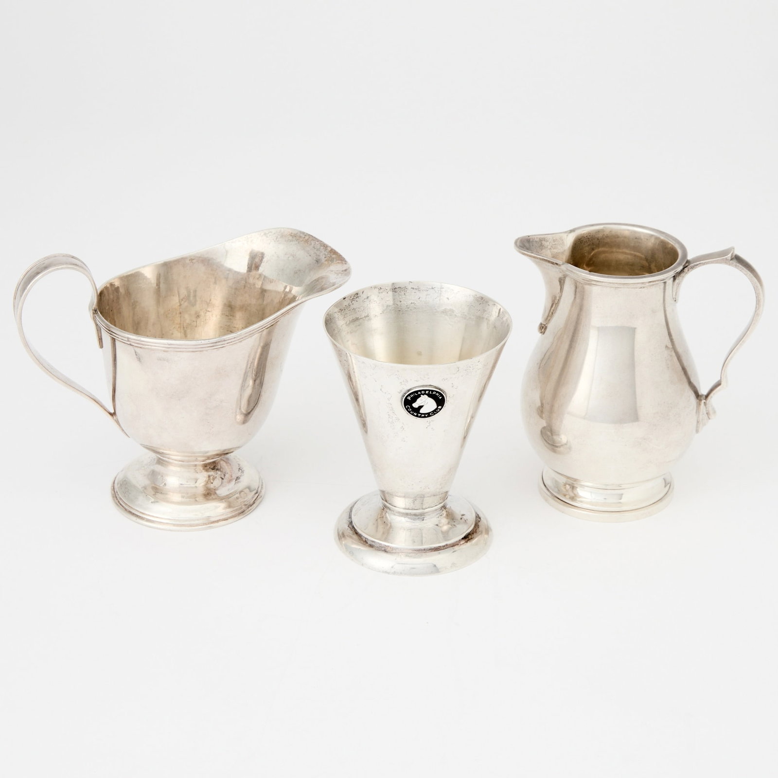Two Tiffany & Co. Sterling Silver Cream Jugs and a Sterling Silver Beaker: Mid 20th century Height of largest 3 3/4 inches, total approximately 11 ounces, all in. * Noted all in due to enamel medallion ot beaker